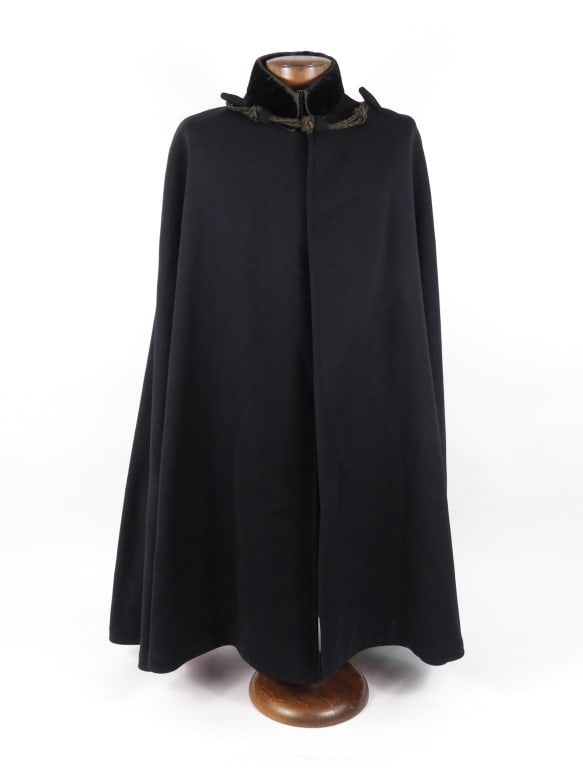 US Navy Boat Cloak: Dark blue wool boat cloak with a rolling collar of dark blue velvet with a double hook and eye closure, a set of mohair frogs with loops and toggles secure the front of the cloak, and a red wool