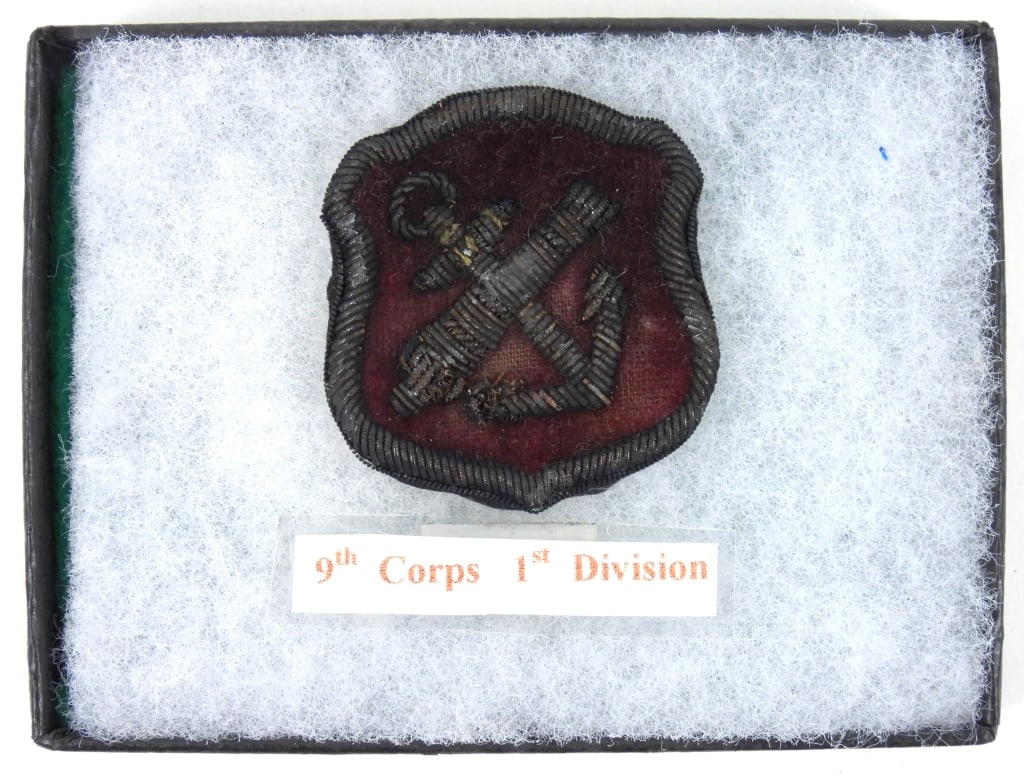 Civil War 9th Corps, 1st Division Badge: Embroidered red velvet badge on a backing with crossed cannon and anchor. United States Overall ht. 1 3/4" Overall wd. 1 5/8"