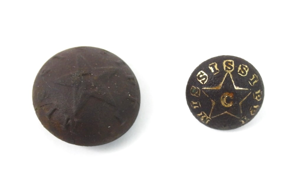 Two Dug Civil War Mississippi Buttons: A cuff-size three-piece button with remnants of gilt wash marked "MISSISSIPPI" with a star and a "C" in the middle, with a "HYDE & GOODRICH" mark on the back and an intact shank; and a coat-size