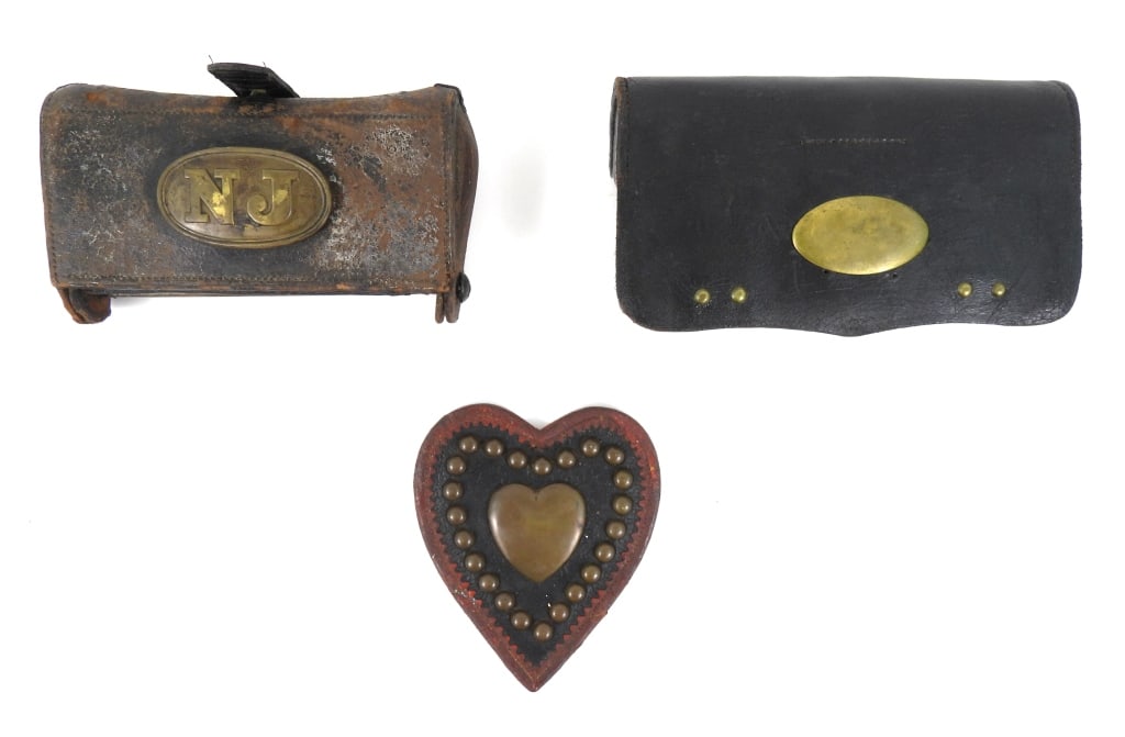 Three Military Leather Items: A McKeever cartridge box with a lead-filled brass plate attached marked "NJ"; a black Japanned cartridge box with an unmarked brass plate on the flap and a 20-hole wooden block on the inside; and a