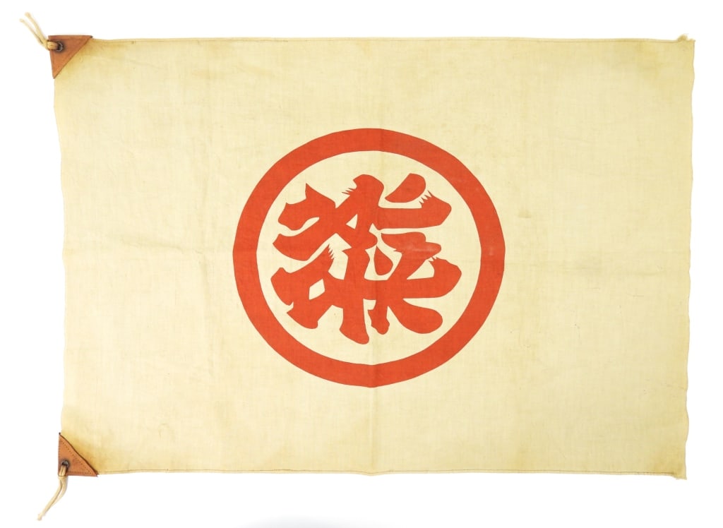 WWII Japanese Kanji Flag: Off-white cotton flag with a red printed symbol, leather reinforcements on each corner, iron grommets, and ties. Japan C. 1939-45 Overall ht. 20" Overall lg. 28"
