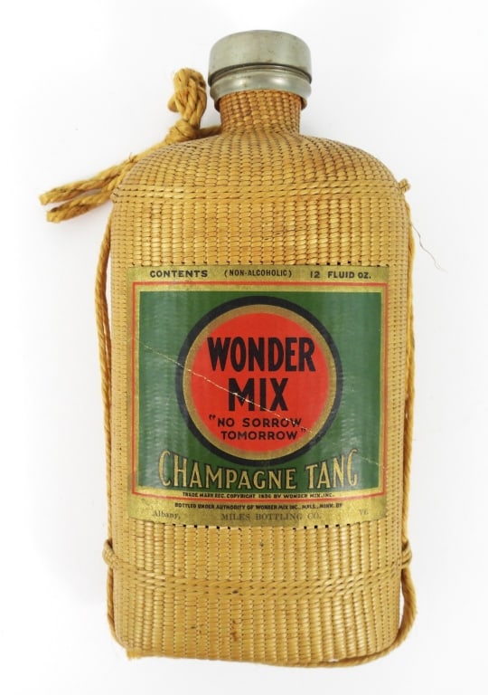 Wonder Mix Wicker-Covered Flask: Wicker-covered, glass flask with aluminum screw cap. Wicker cover is intact with twine strap . Original "Wonder Mix" label, with "Champagne Tang" and "Copyright 1936" and "Miles Bottling Co." Bottle
