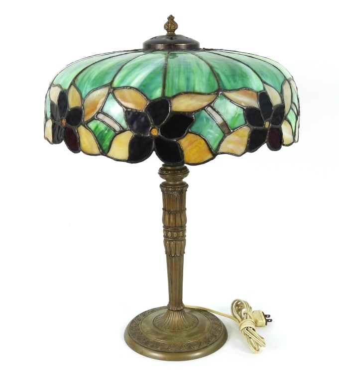 Whaley Style Lead Glass Table Lamp: Antique art nouveau base with floral pattern slag glass shade. Red flowers accented by amber / yellow and green segments. Shade rests on a crown collar. Base is cast metal with bronze finish affixed o