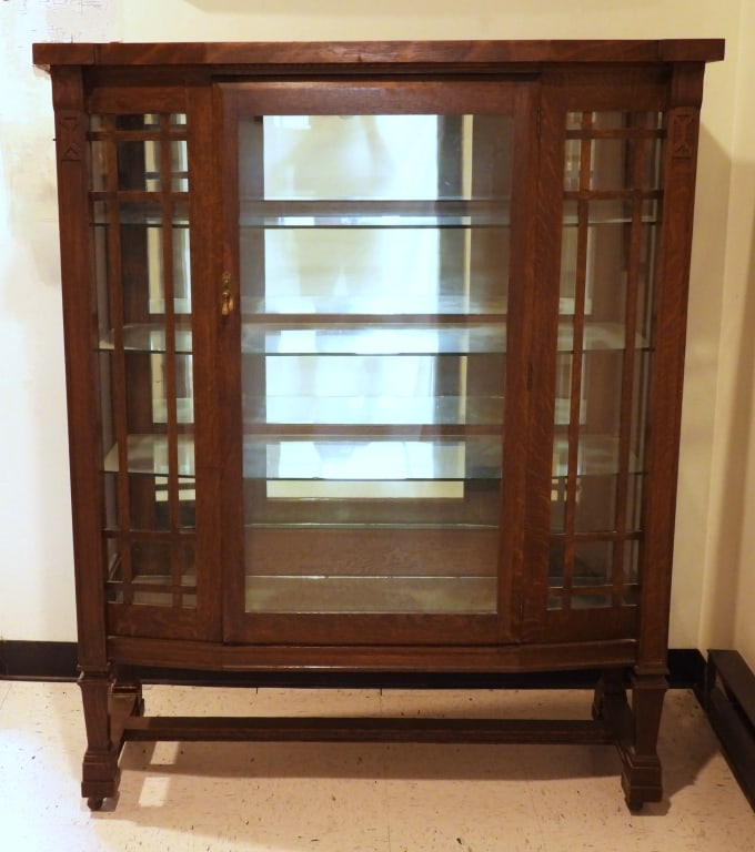 Antique Arts & Crafts Display Cabinet: Quarter sawn hand carved oak with stretcher base and glass panels having 3 glass shelves. With casters. Measures 58-1/2" high x 48" wide, x 17" deep.
