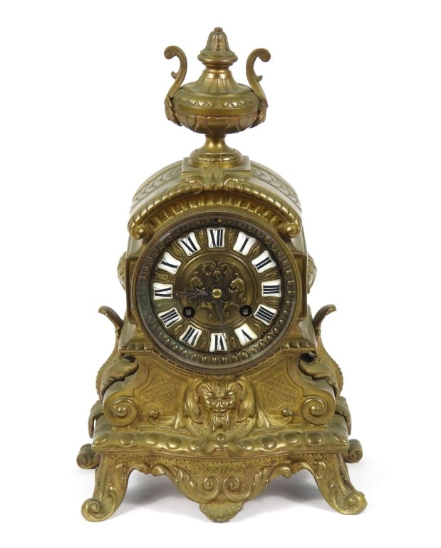 19th-C French Gilt Bronze Mantel Clock: Ornate gilt bronze mantel clock with urn finial over acanthus leaf handles, North Wind center medallion, and ornate feet housing a decorative gilt face with Roman Numeral cabochons. Movement marked "1