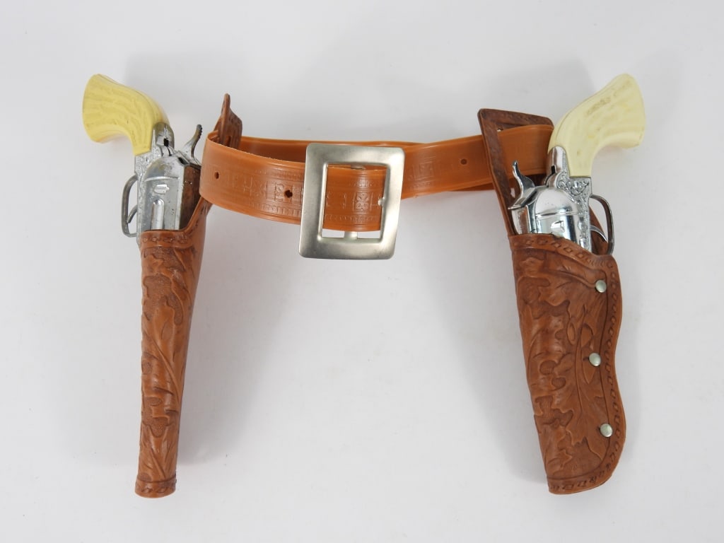 PR Hubley Pony Boy Cap Guns w/ Holsters: Pair of vintage Pony Boy toy cap guns with white faux bone grips and holster belt. Guns 4 1/4" t x 9" w x 1 1/4" d.