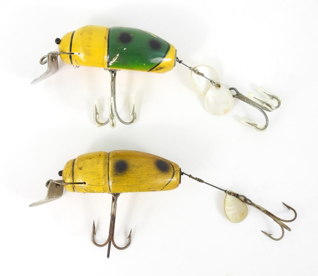 Two Creek Chub Bait Co. 3800 Series Lures: Wood beetle lures. One is 5-1/2" long with hooks extended painted green and yellow with hook guards. Has finish stains and cracking with impact dings. Also a 6" long with hooks extended painted