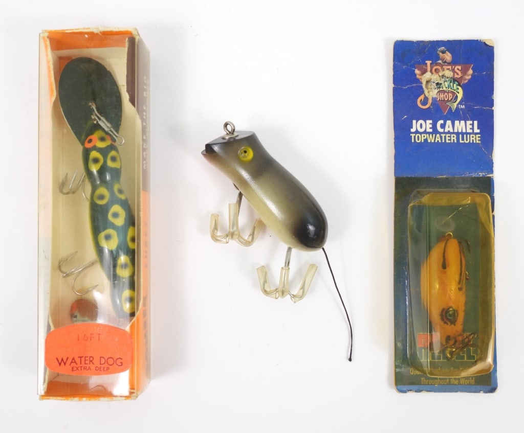 3 Vintage Fishing Lures: An original boxed 16 ft extra deep Water Dog by Bomber that measures 4-1/2" long in new condition. A 2-1/2" Shakespeare Glo-Lite Swimming Mouse new condition. An unopened Rebel Joe Camel top water