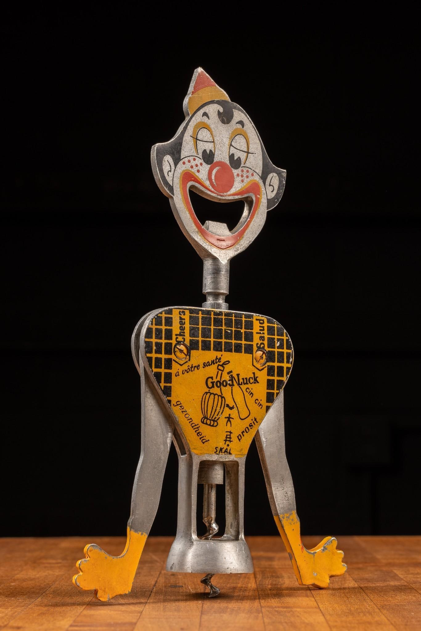 1950 Carlo Gemelli Patented Bottle Opener and Corkscrew: Italian-made aluminum double lever corkscrew and bottle opener in the shape of a clown. Notable here is the translation of different cheers across the front of this piece, something that became standa