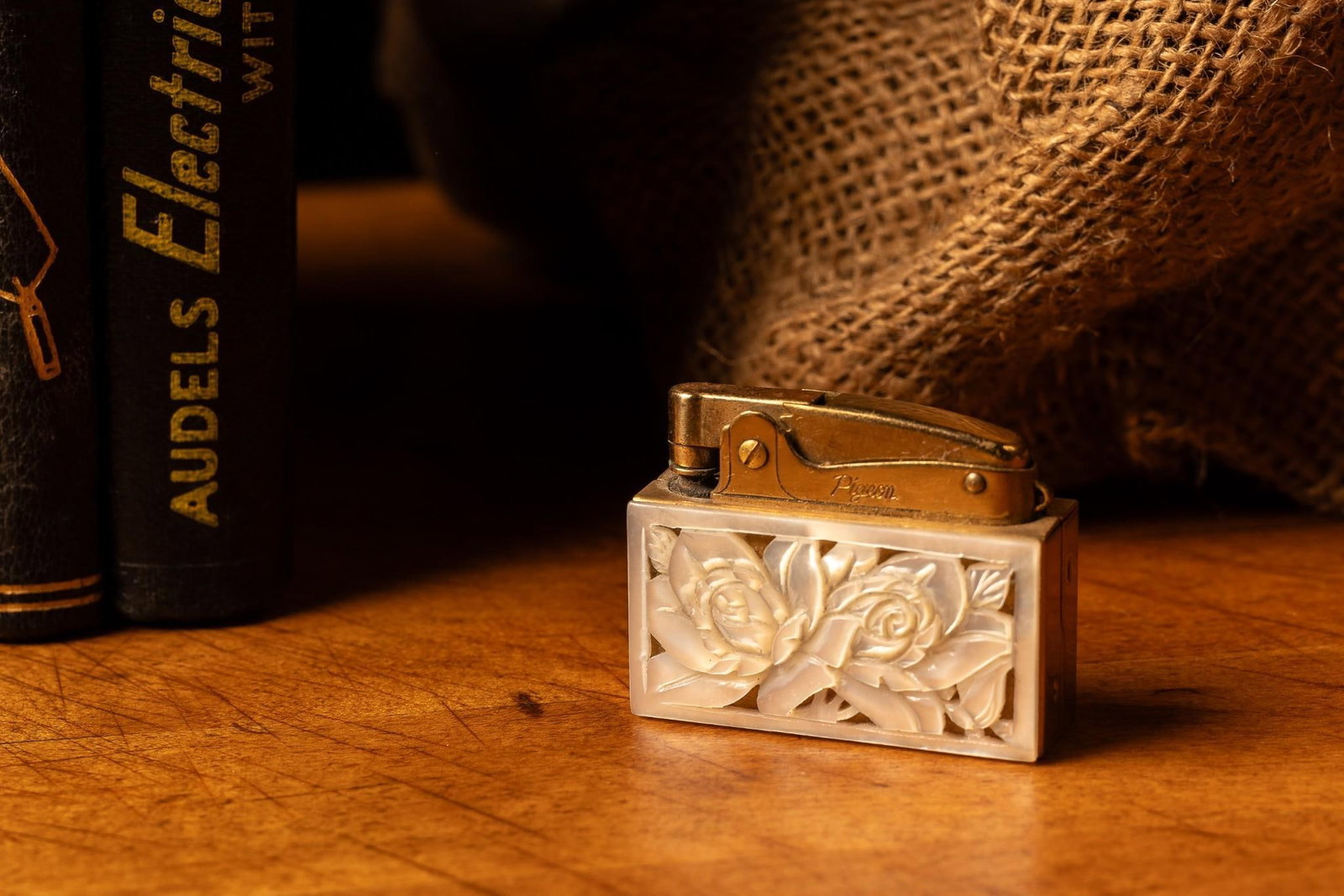 Small Pigeon Rose Lighter: Pigeon-produced pocket lighter with pearlescent carved roses. This lighter may require flint or other mechanical parts. All lighters are sold as-is. All lighters are sold without fuel. 2" W x 1.5&