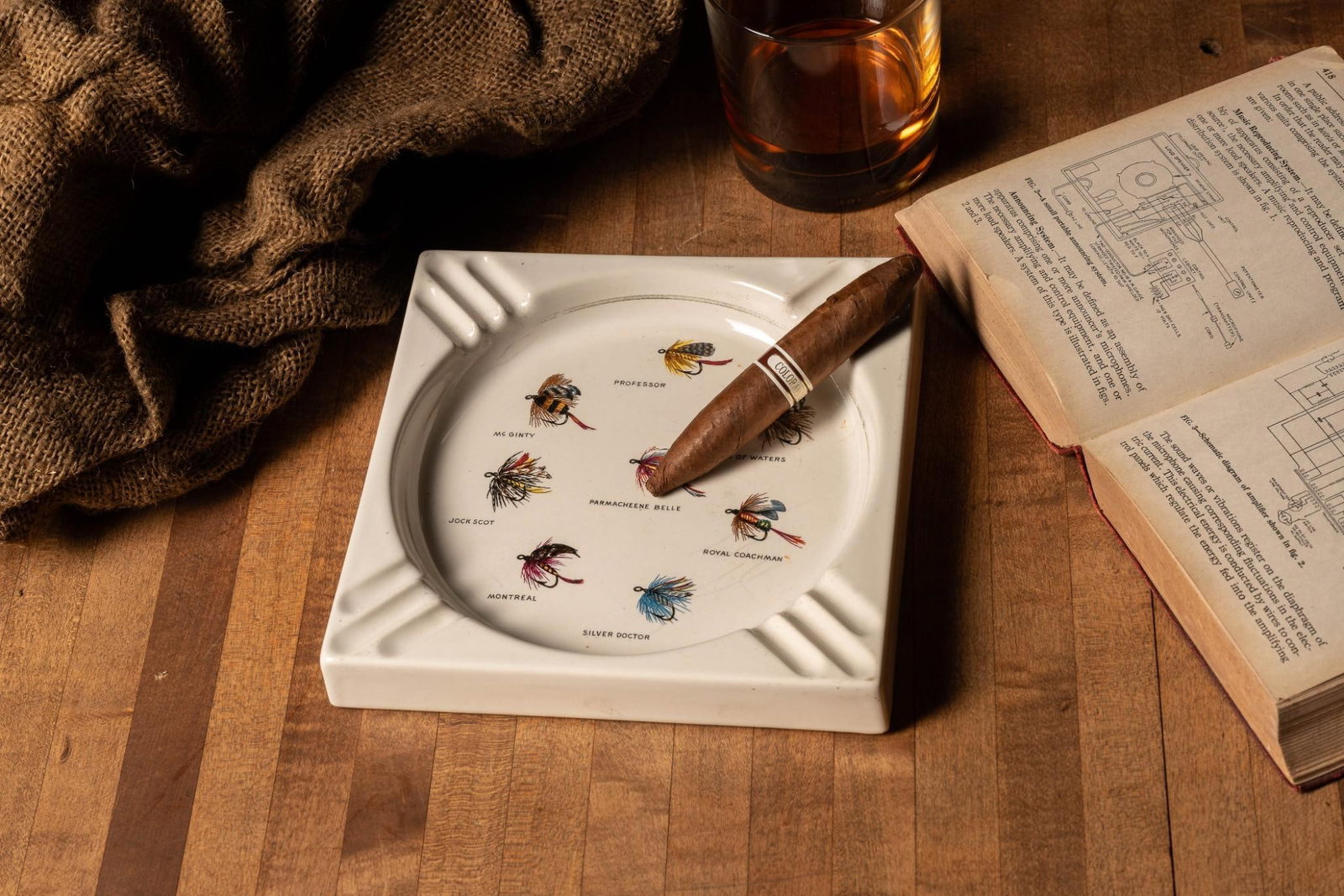 Vintage Fishing Lure Ashtray: Vintage square ashtray embellished with painting depicting various types of fishing lures. Exhibits minor signs of wear including light crazing and missing portions from cork bottom. 7.25" W x 7.2