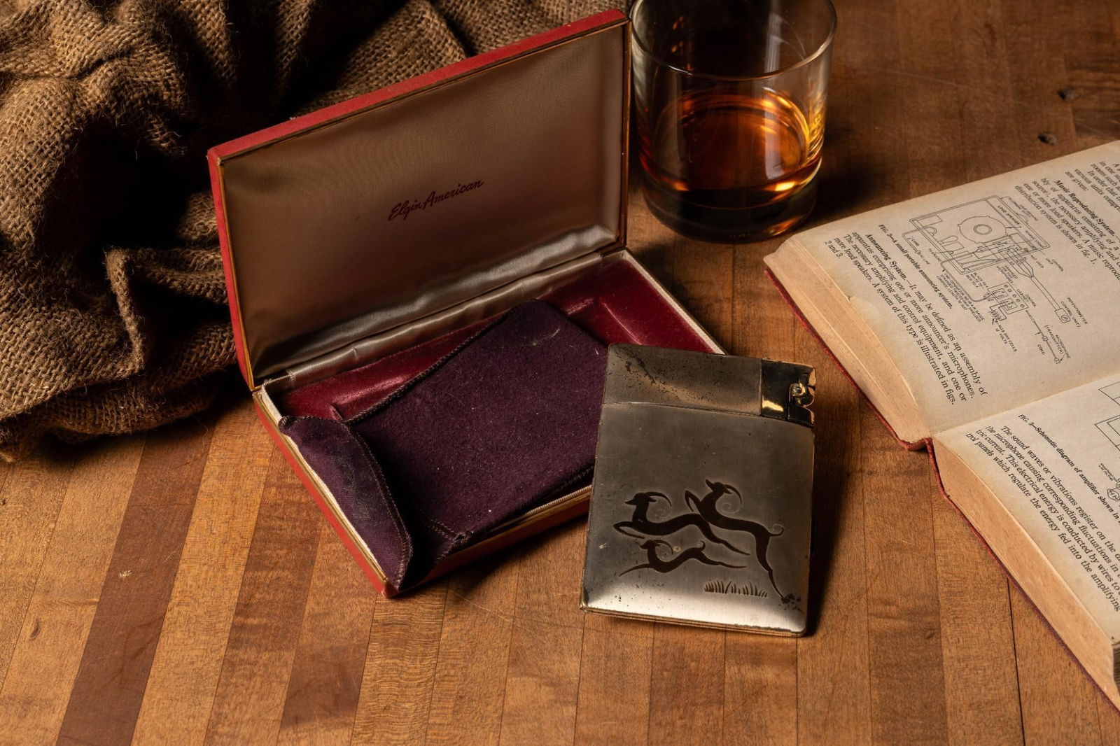 Vintage Elgin American Cigarette Box with Gold Wash Vermeil: Vintage cigarette case with stylized prancing deer accents. Comes with original box and carrying bag. Exhibits minor tarnish and scuffs.