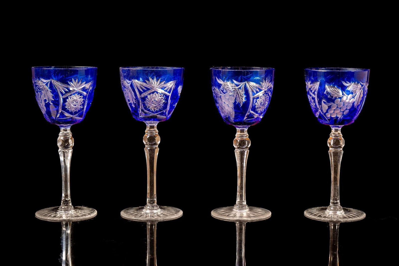 Set of 4 Ajka Crystal Marsala Cobalt Blue Cut to Clear Wine Goblet Glasses: Sapphire blue-tinted glass with cut to clear fractal and floral design motifs. Appear to be free from cracks or chips, but exhibit minor scratches.