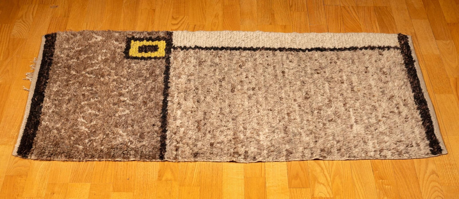 Brown Woven Rug with Yellow Accent: Rough, woven area rug in brown with a small yellow rectangular accent. Exhibits minor signs of wear consistent with age and use. 54" W x 24" D