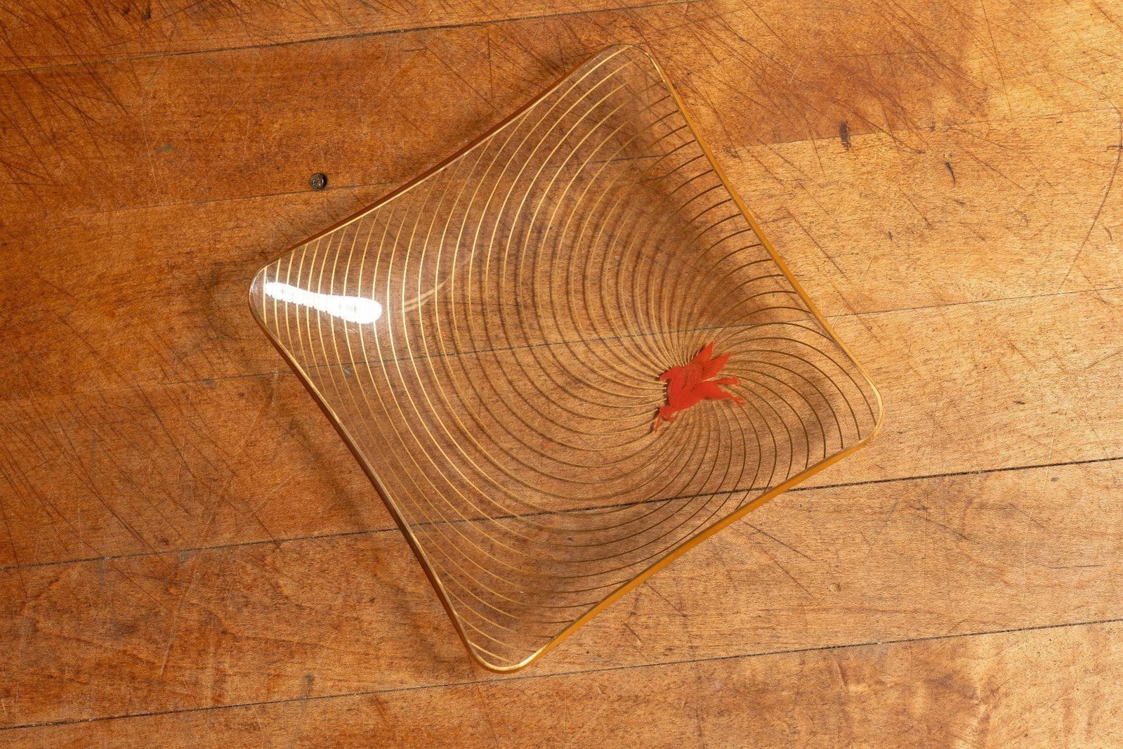 Mobil Pegasus Glass Ashtray w/ Gold Striping 2: Item SKU: C-8239 Vintage glass ashtray with gold stripes spiraling into the iconic Mobil Pegasus logo in red. The glass ashtray also has gold striping around the edge. 4.5" x 4.5"