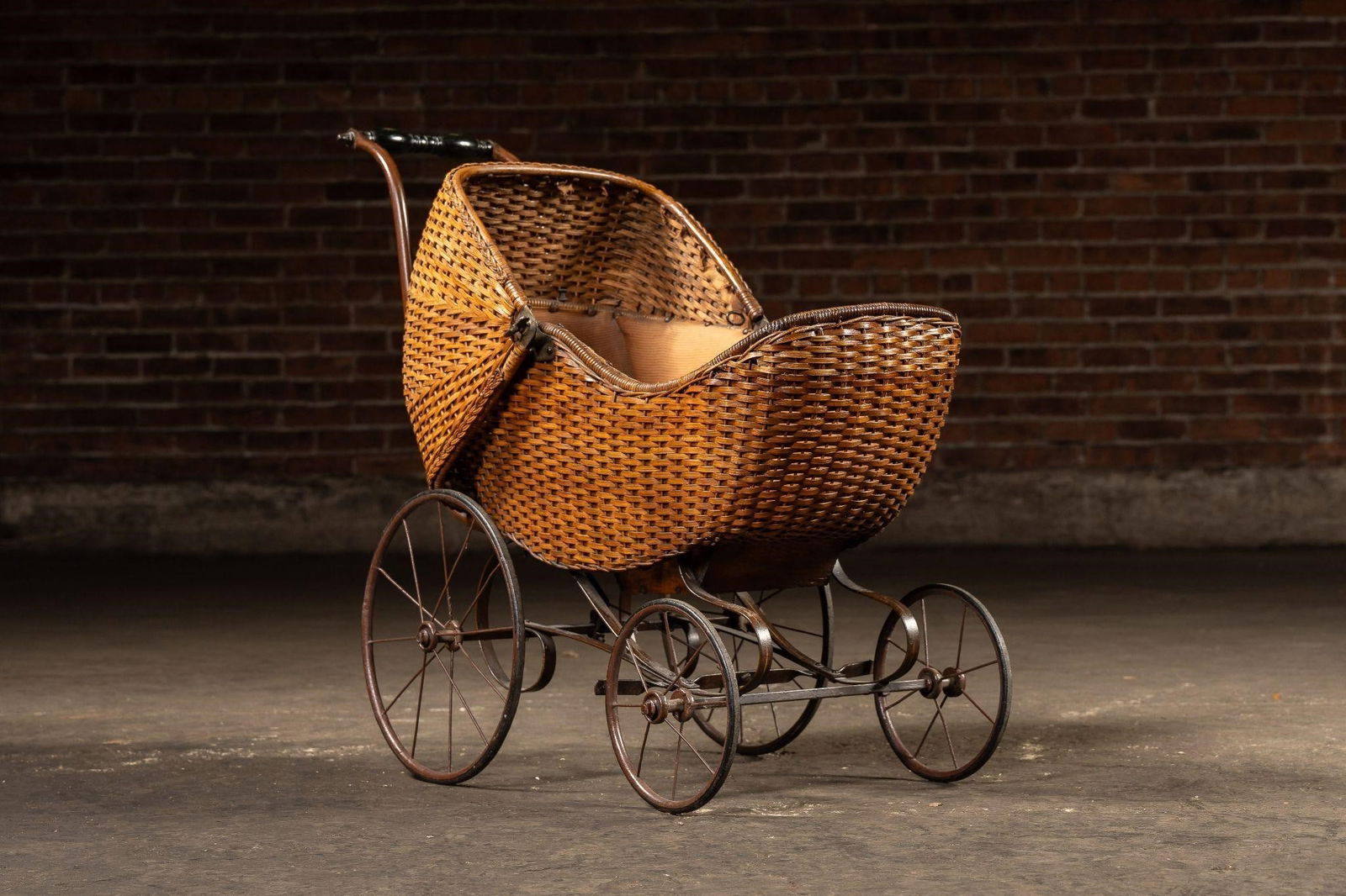 Antique Rattan Baby Carriage: NOTE: For an accurate in-house shipping quote on this lot, please reach out to us at rockauctiongallery@gmail.com. Item SKU: C-14096 This antique baby carriage features a woven rattan body with a curv