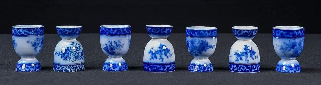 Set of Seven Victorian Flow Blue Egg Cups: NOTE: For an accurate in-house shipping quote on this lot, please reach out to us at rockauctiongallery@gmail.com. Item SKU: C-17562 Set of seven flow blue egg cups with floral decoration. This assemb