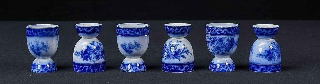 Set of Six Victorian Flow Blue Egg Cups: NOTE: For an accurate in-house shipping quote on this lot, please reach out to us at rockauctiongallery@gmail.com. Item SKU: C-17564 Set of six flow blue egg cups with floral decoration. This assemble