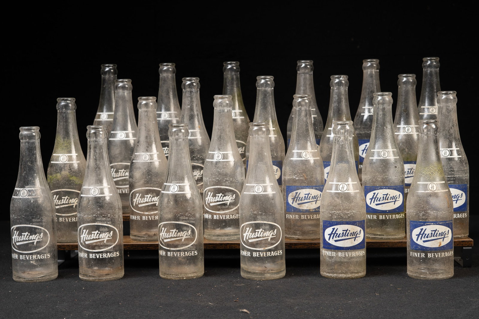 Set of 24 'Hustings' Glass Bottles with Crate: **NOTE: Any shipping quotes provided on this screen are provided by Live Auctioneers. For an in-house shipping quote on this lot, please reach out to us at rockauctiongallery@gmail.com.** C-19299