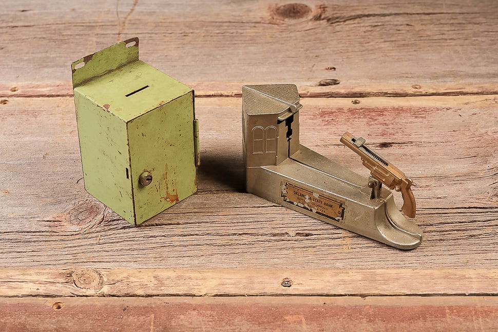 Lot of 2 Metal Coin Banks, Square and Pistol Bank: **NOTE: Any shipping quotes provided on this screen are provided by Live Auctioneers. For an in-house shipping quote on this lot, please reach out to us at rockauctiongallery@gmail.com.** C-19471