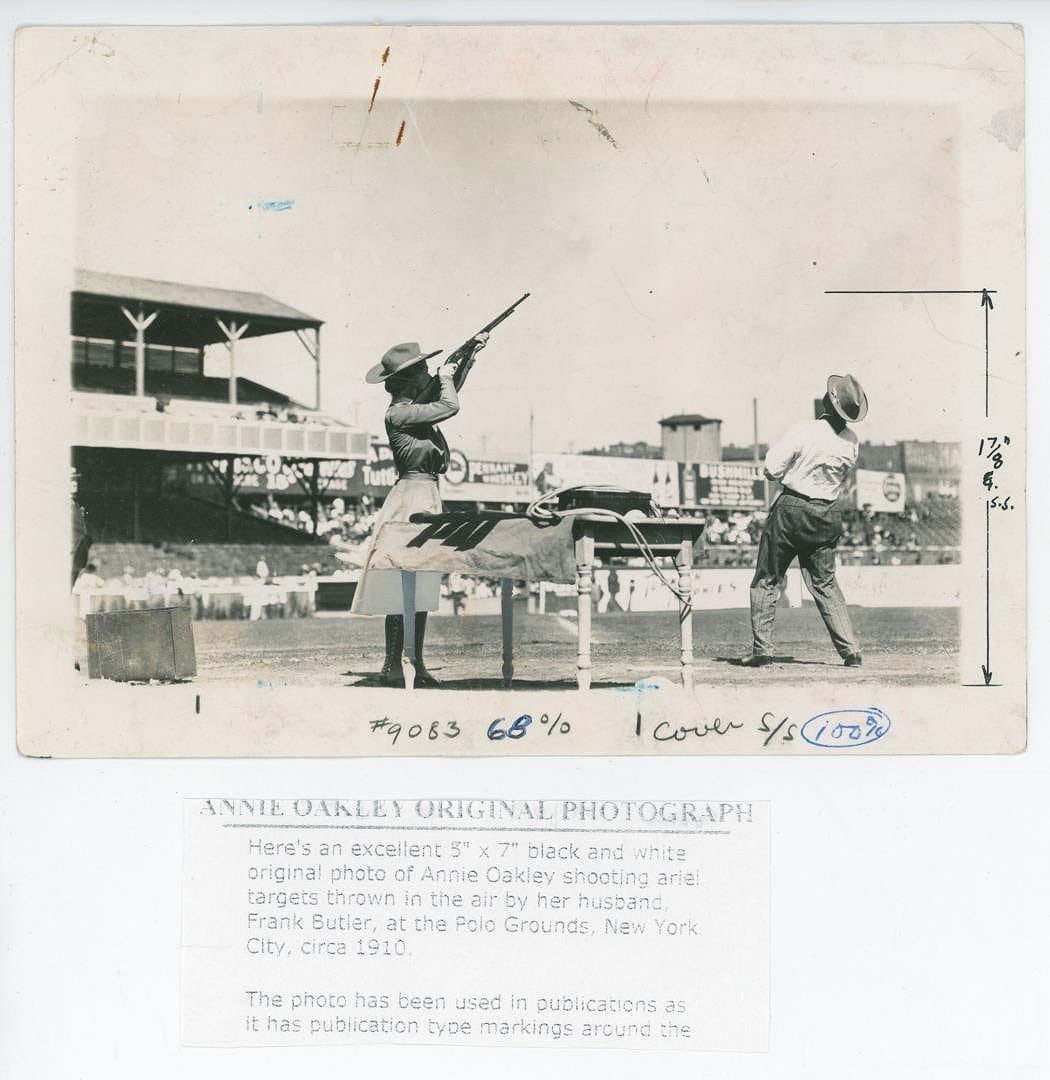 1910 Annie Oakley Polo Grounds Shooting Photo: 5" by 7". Nice original press photo. Annie Oakley competing in a trapshooting exhibition at the Polo Grounds in New York City in 1910. She is shown aiming a Remington Model 12 .22 caliber pump-action 