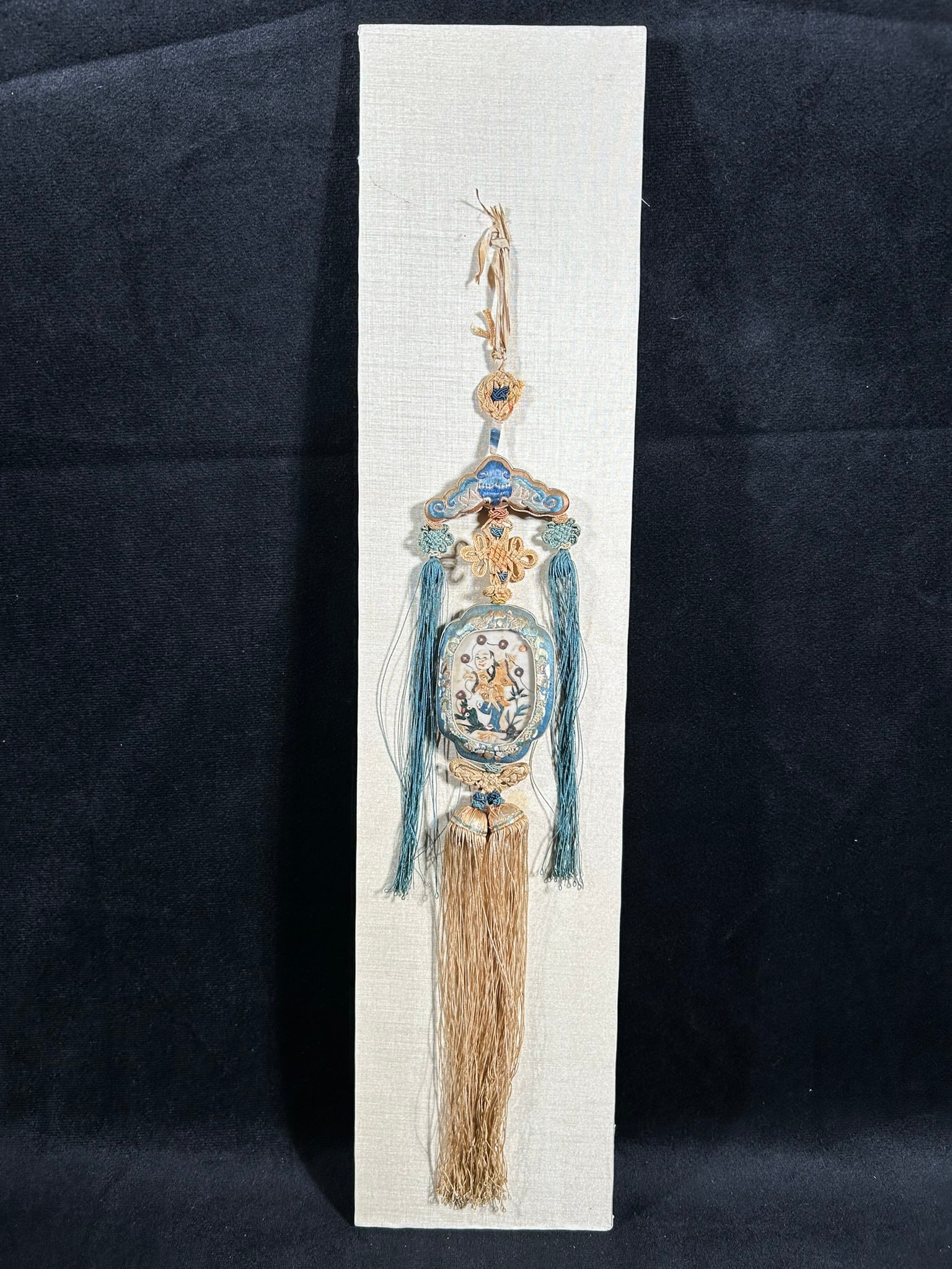 An Embroidered Silk 'Liu Hai and Toad' Pendent and Box, Qing Dynasty: The pendent: 16.1/4 in. (64 cm.) long; the box: 20 in. (51 cm.) long, 4.7/8 in. (12.5 cm.) wide, 2.1/8 in. (5.3 cm.) high.