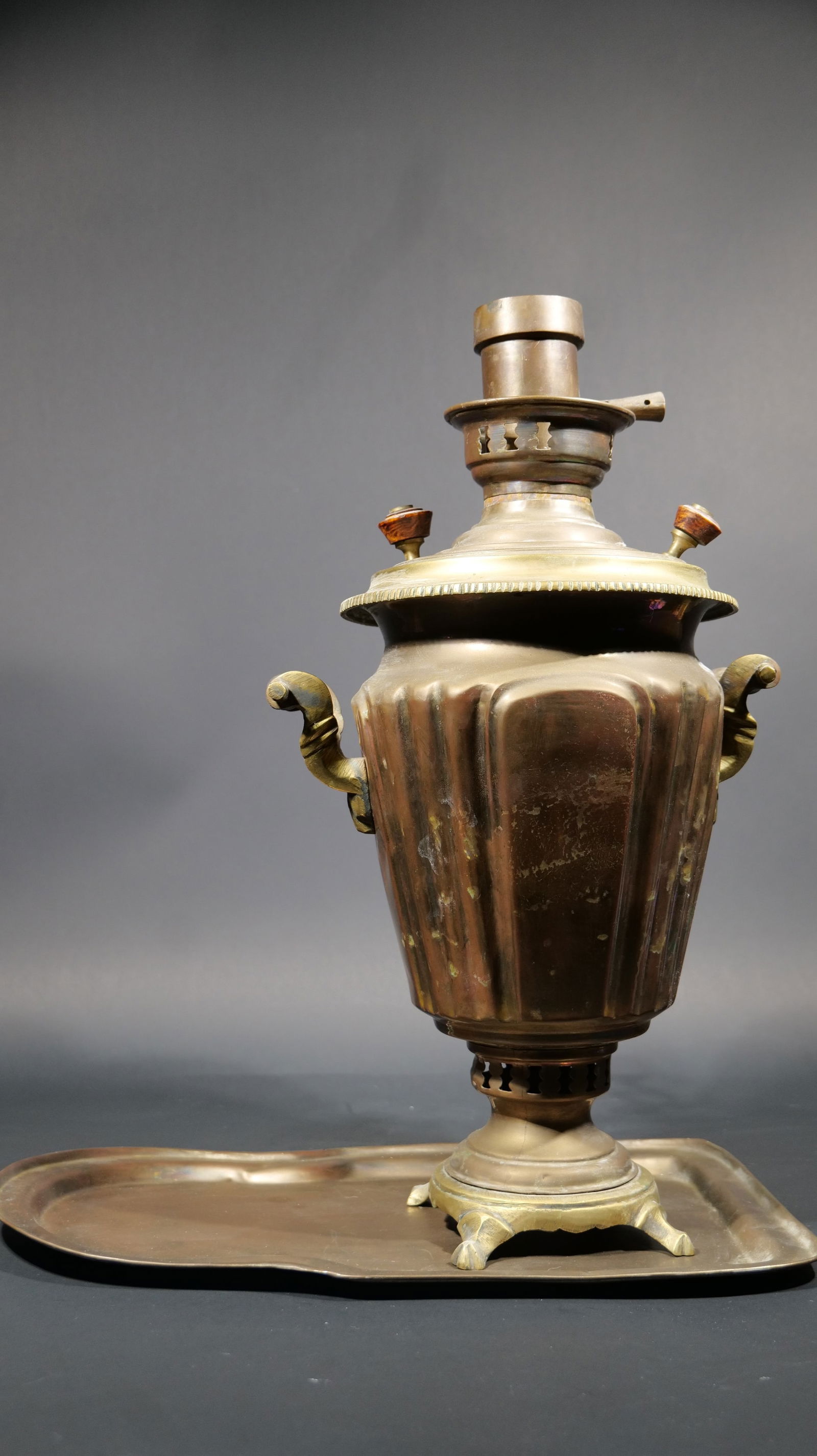 An Antique Russian Brass 'Pakkaron Maged' Samovar and Base Tray: With a stamp of 'Pakkaron Maged' stamp on the cover. The height of the the teapot itself is 20 inches and the width is 10.5 inches. The tray itself has a length of 16.8 inches, and a width of 10 inche