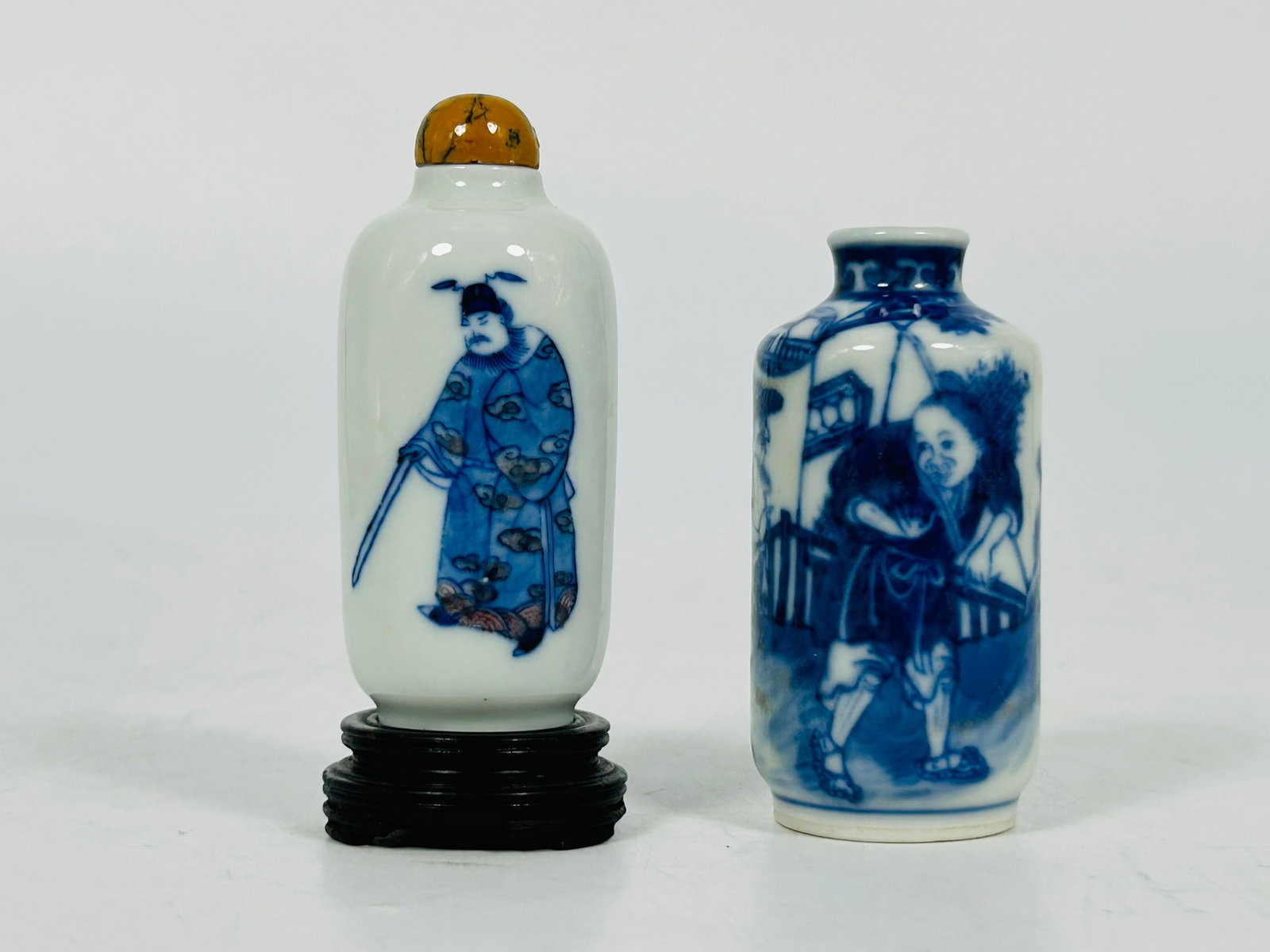 Two Chinese Blue and White Snuff Bottles: One snuff bottle with wood base is 3.75 in. high, 1.4 in. wide. Another snuff bottle is 3 in. high, 1.5 in. wide.