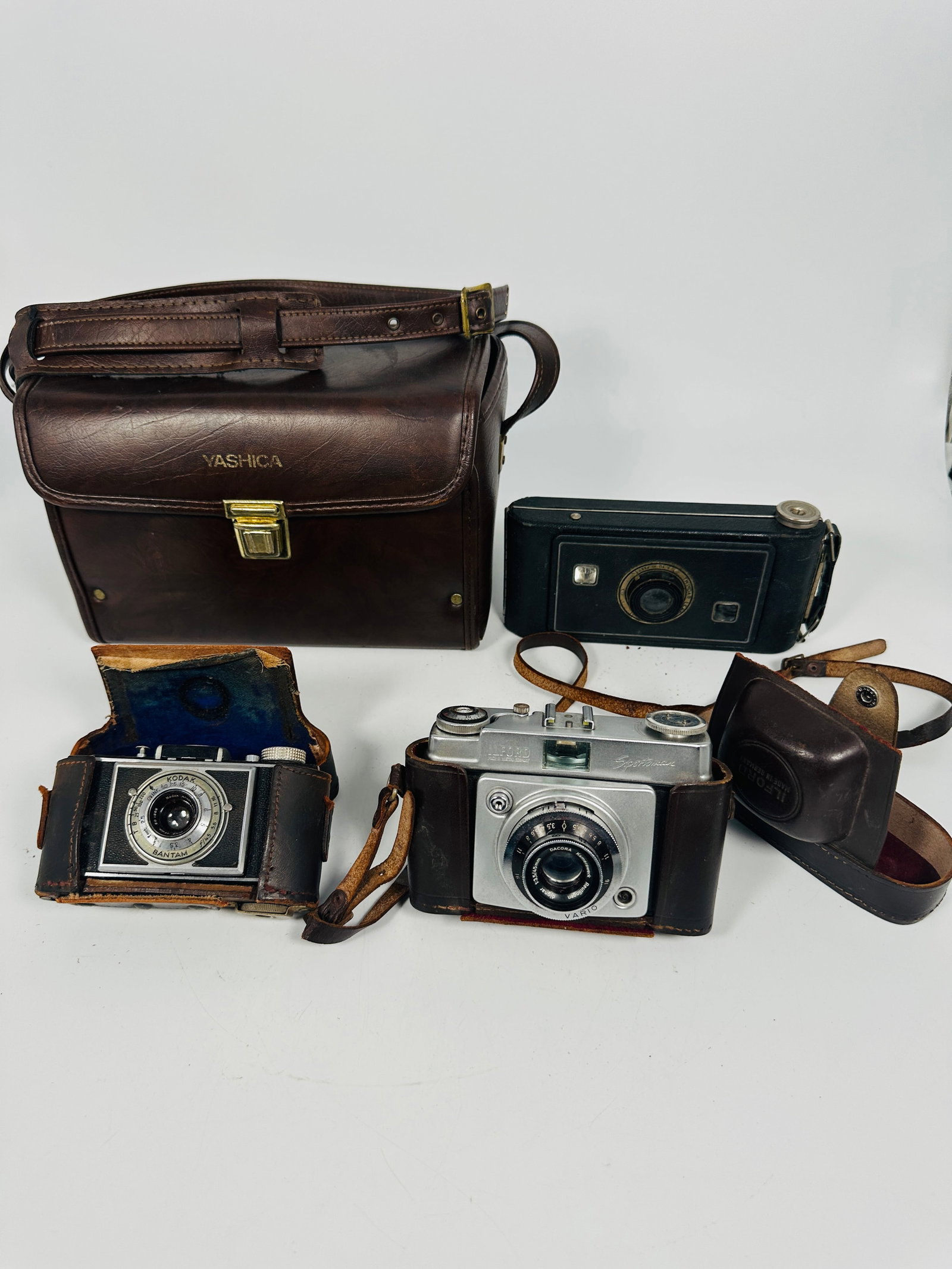 A Group of Four Vintage Cameras: Comprising a Kodak Bantam Camera with field leather case, with a mark of the owner 'Vincent Guido' and a US army service number; a Vintage Ilford Sportsman 35mm Camera and Dacora Vario 1:2.8/45 mm Len