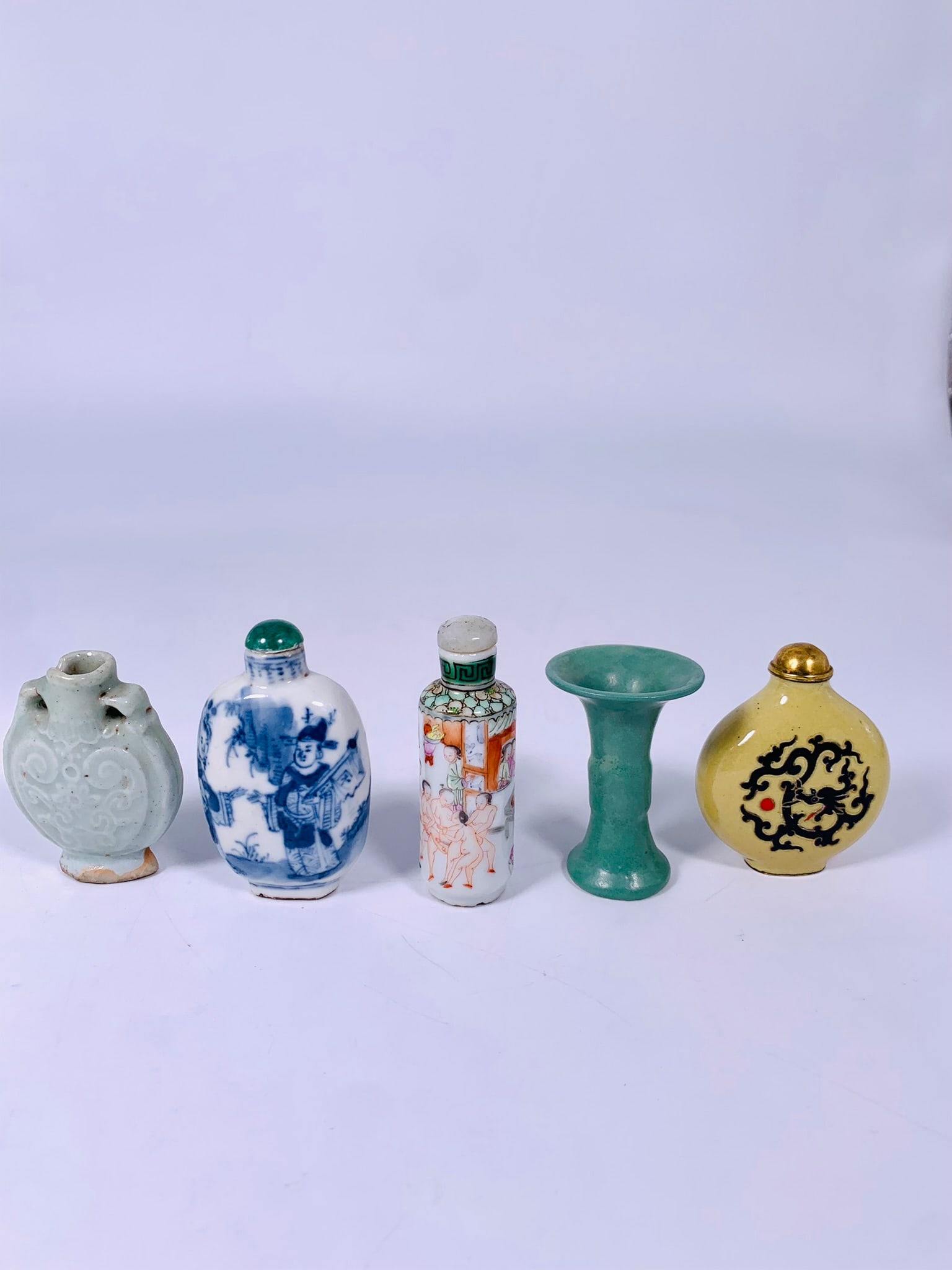 A Group of Five Porcelain Table Articles: Comprising a group of four snuff bottles, the famille rose 'erotic subject' snuff bottle measures 3 in. high, 1.1/8 in. wide; the blue and white 'figural' snuff bottle measures 2.7/8 in. high, 1.3/4 i