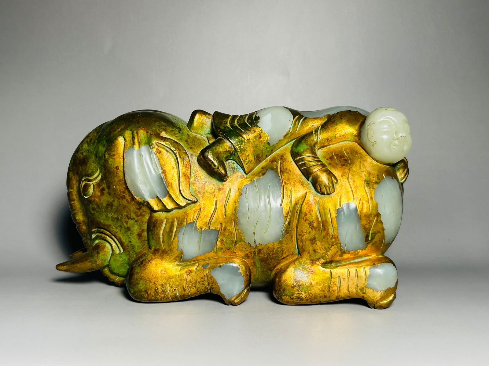 A Pale White Jade Gilt-Decorated Figure of Elephant and Rider Group: 4.3/8 in. high, 8 in. wide.
