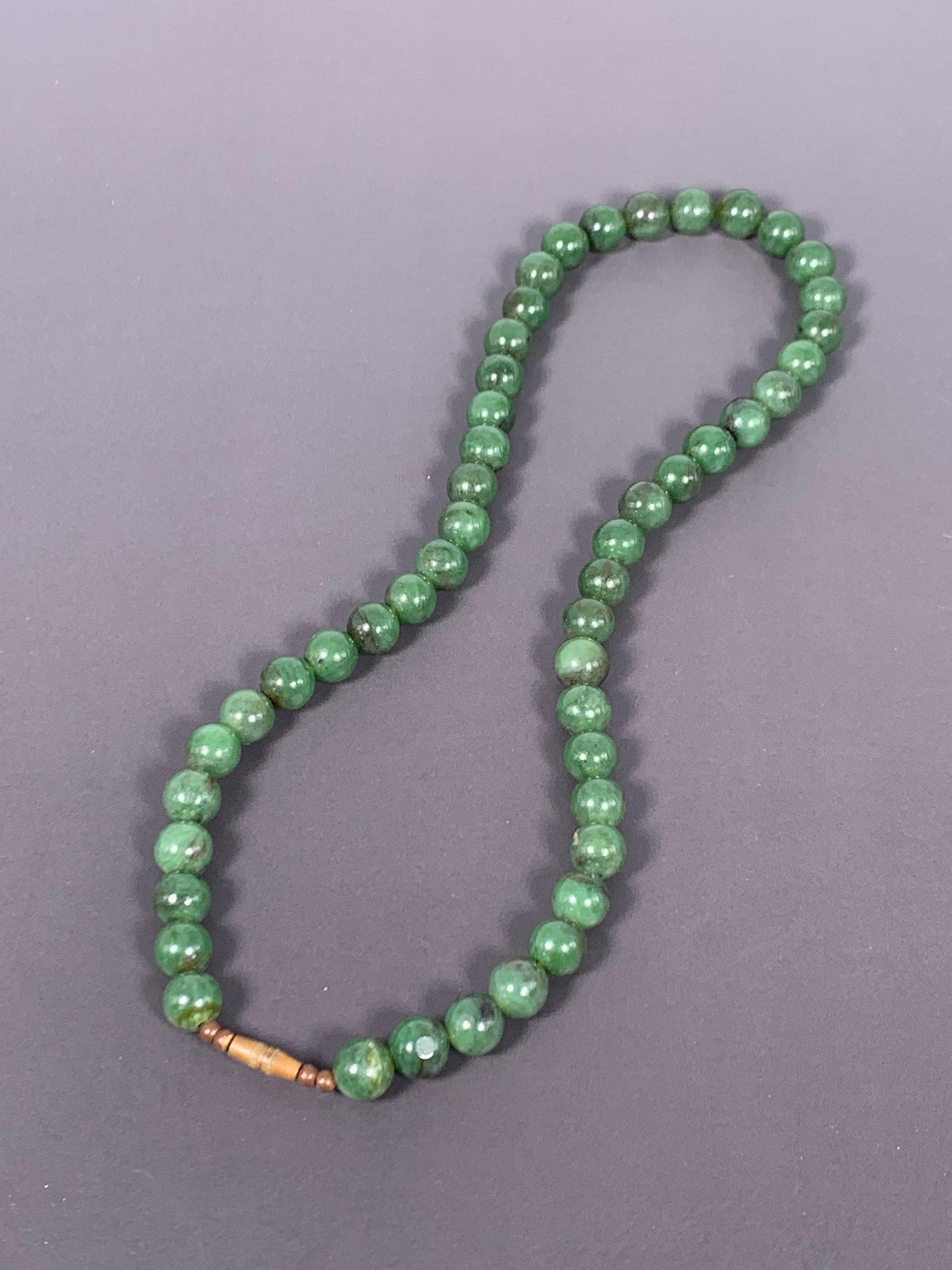 A Chinese String of Green Jade Beads, Necklace: The necklace consists of forty-nine green jade beads, measure 1/4 in. diam. each.