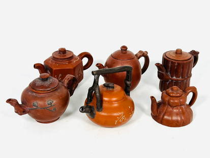 A Group of Six Chinese Small Yixing Teapots and Covers: Comprising a teapot and cover with Chinese characters 'spring stream', 3.1/2 in. high, 3.5/8 in. wide; a hexagonal teapot and cover, 2.3/4 in. high, 4.3/8 in. wide; a 'flower branch' teapot and cover,