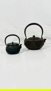 Two Japanese Cast Iron Teapots and Covers: Comprising a larger teapot and cover, no marks visible, 7.1/2 in. high, 6.3/4 in. wide with handle erected; a smaller teapot and cover, a mark of 'Japan' to the back of the cover, 5 in. high, 4.3/8 in