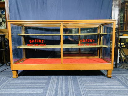 An Antique Large Oak Floor Showcase: With brand name 'Branu's Wheat King Bread' to the front glass panels. It has two cloth-wrapped shelves, with an additional shelf at the bottom for display.40 in. high, 72 in. wide, 24 in. deep.