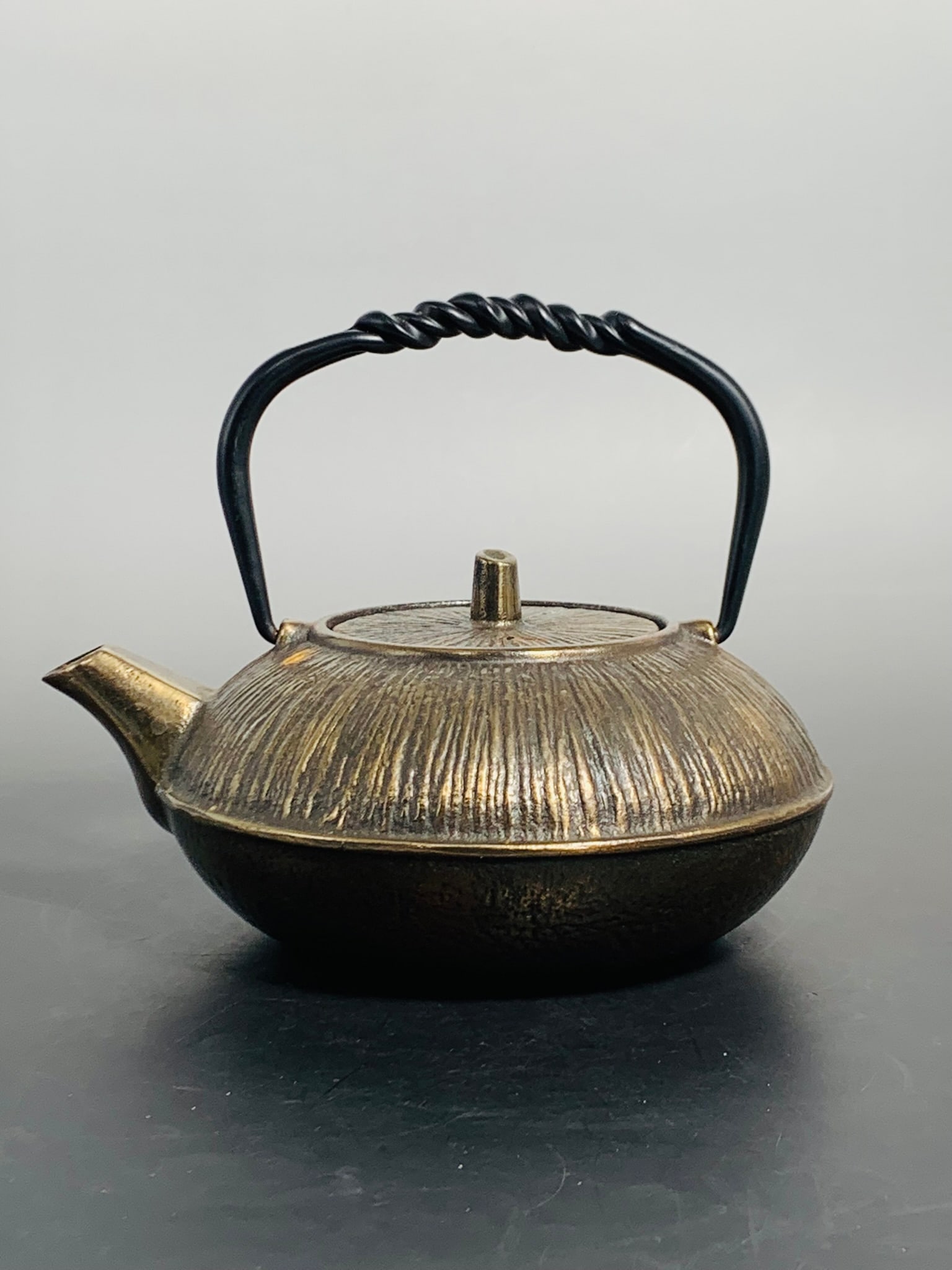 A Japanese Cast Iron Teapot and Cover: 6.1/4 in. high, 7.3/4 in. wide with handle erected.