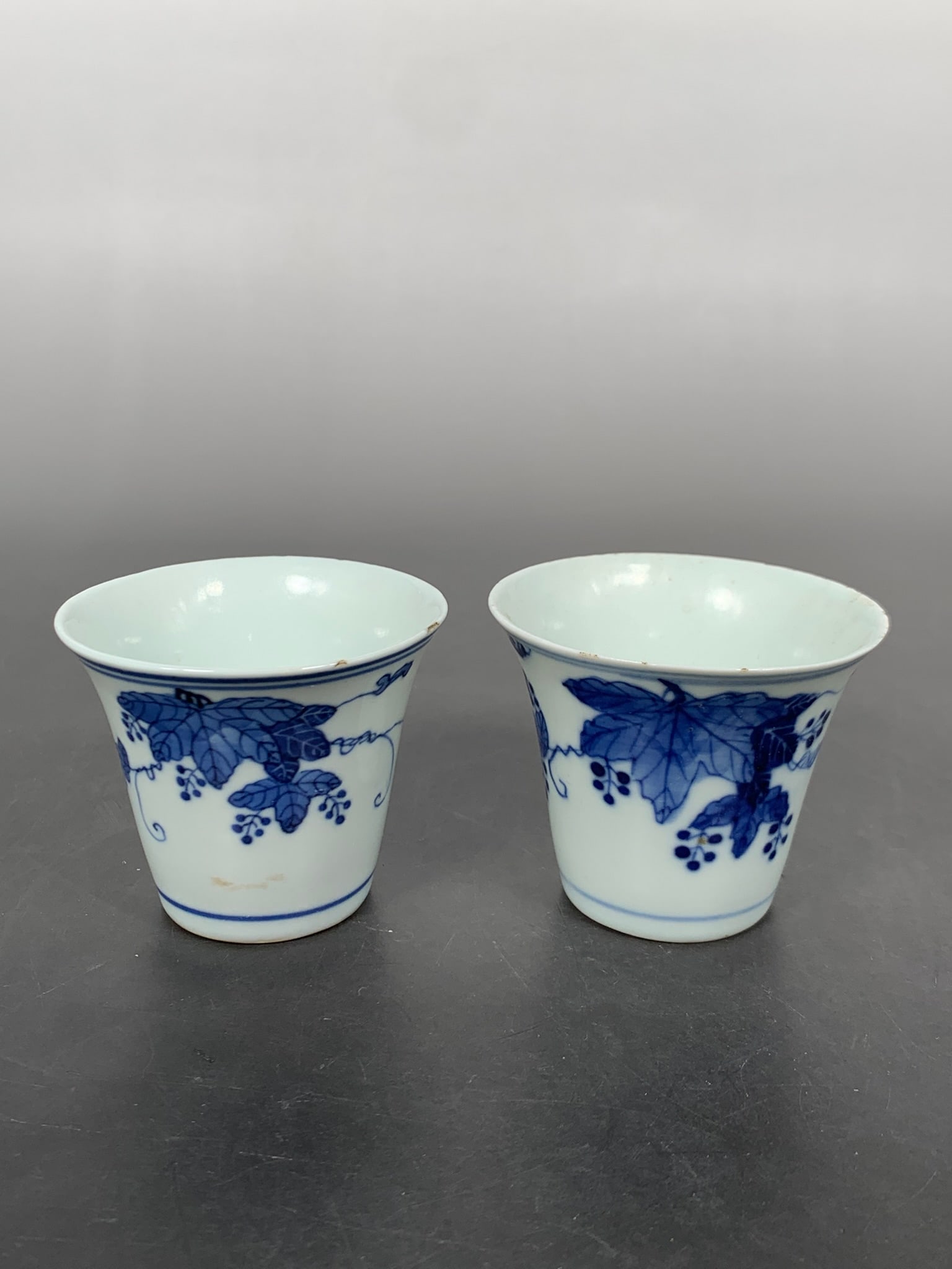 Two Chinese Blue and White 'Grape and Vine' Cups: The larger one measures 2.3/8 in. high, 2.7/8 in. wide; the smaller one measures 2.1/4 in. high, 2.7/8 in. wide.