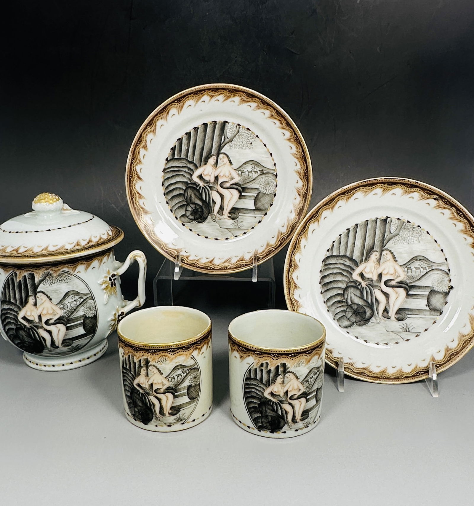 A Chinese Grisaille-Decorated Tea Set (Part), 18th Century: Comprising a pair of dishes, 6.1/8 in. diam. each; a pair of tea cups, 2.1/2 in. high, 3.3/8 in. wide each; and a two-handled cup and cover, 5.1/2 in. high, 6 in. wide.