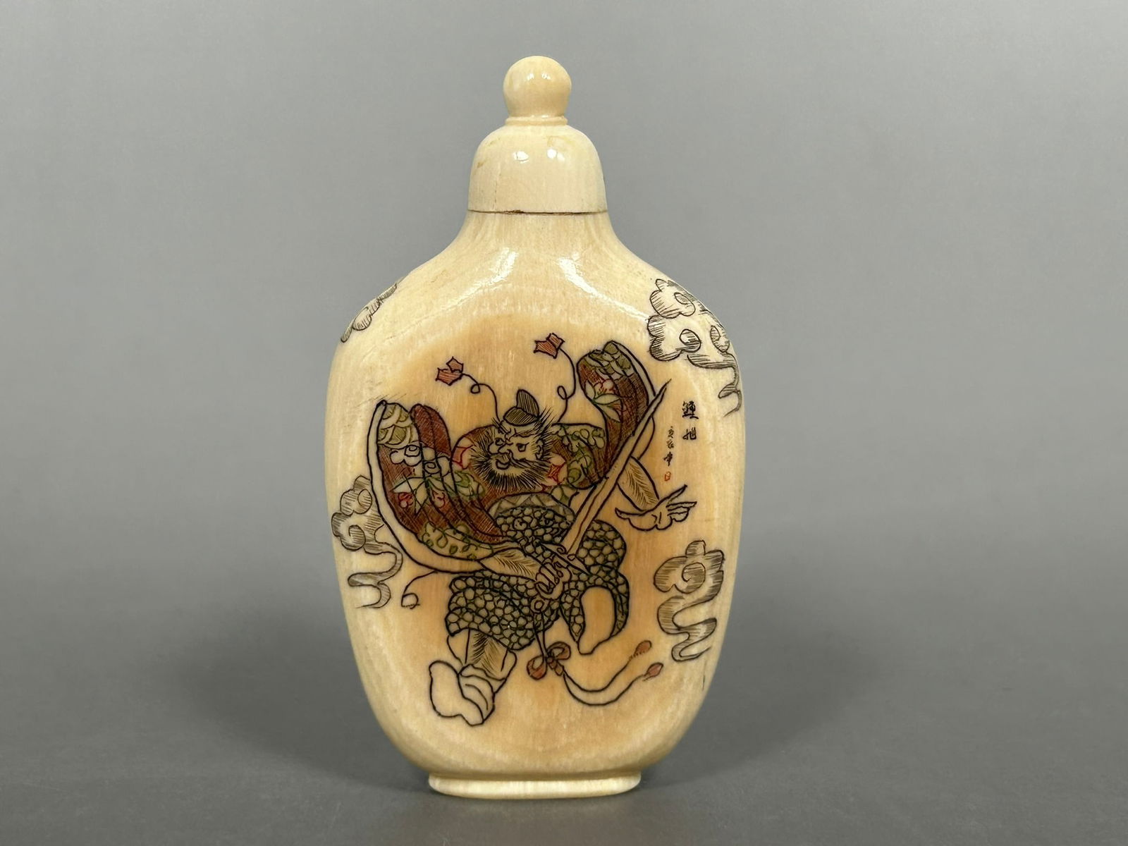 A Chinese Snuff Bottle: Engraved with Zhong Kui on the front side and inscription on the reverse side. 2.1/2 in. high, 1.1/2 in. wide.