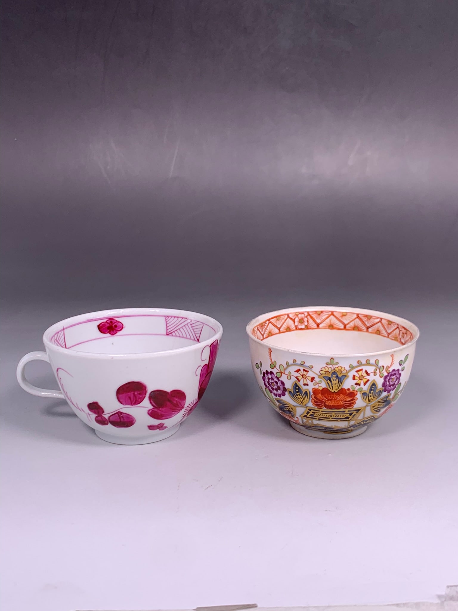 Two Porcelain Cups: Comprising a cobalt and gilt-decorated 'floral' cup, 18th century, Wallendorf mark to the base, 1.7/8 in. high, 3 in. diam.; and a puce tone cup with one handle, 1.7/8 in. high, 3.3/4 in. wide.
