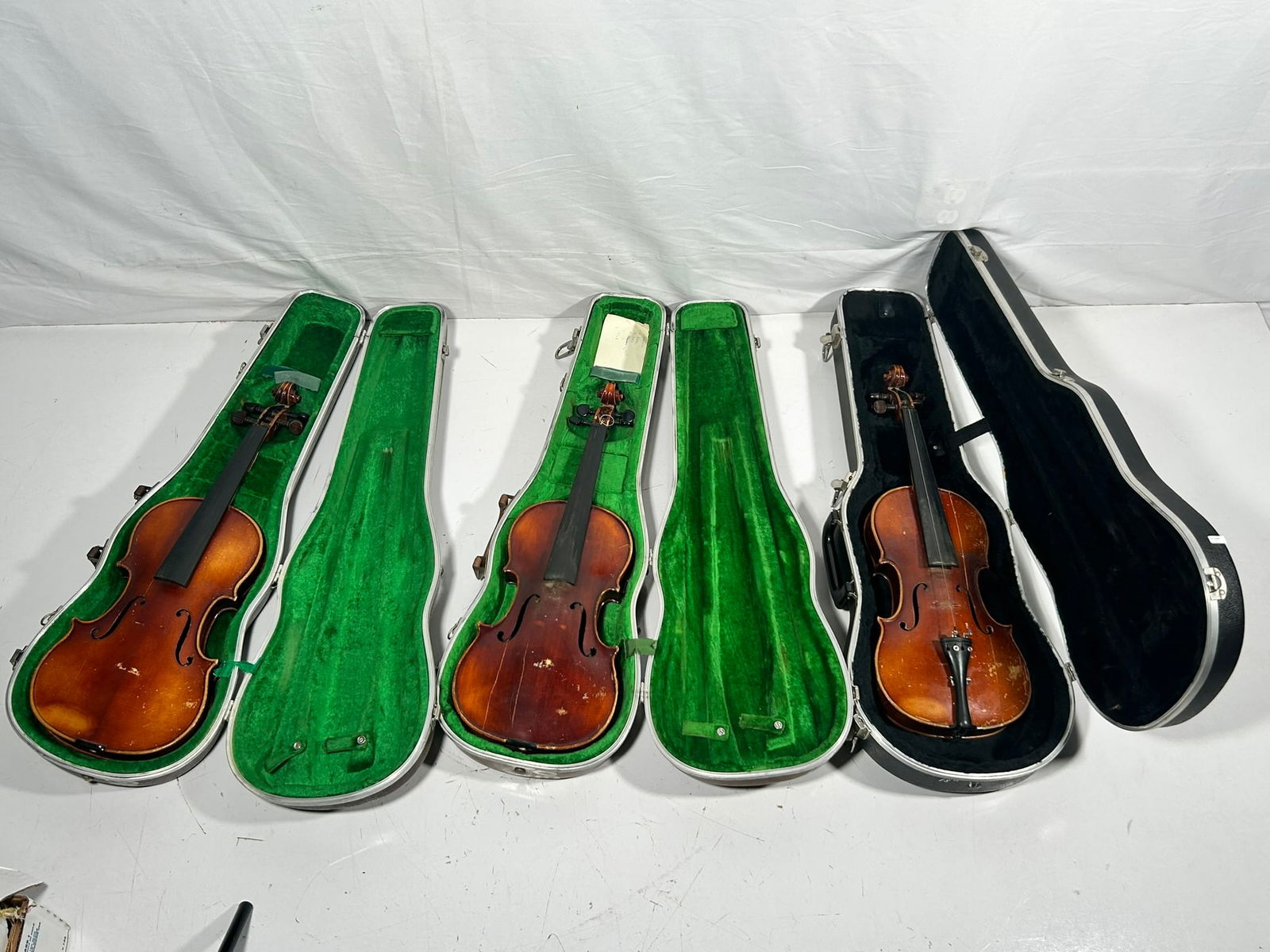A Group of Three Vintage Violins: Comprising a John Juzek Violin Maker formerly in Prague, Made in Germany, with a carrying case with a mark of Wagner High School and another mark of BD. of ED. N.Y.C, 24 in. long, 8.1/4 in. wide for t