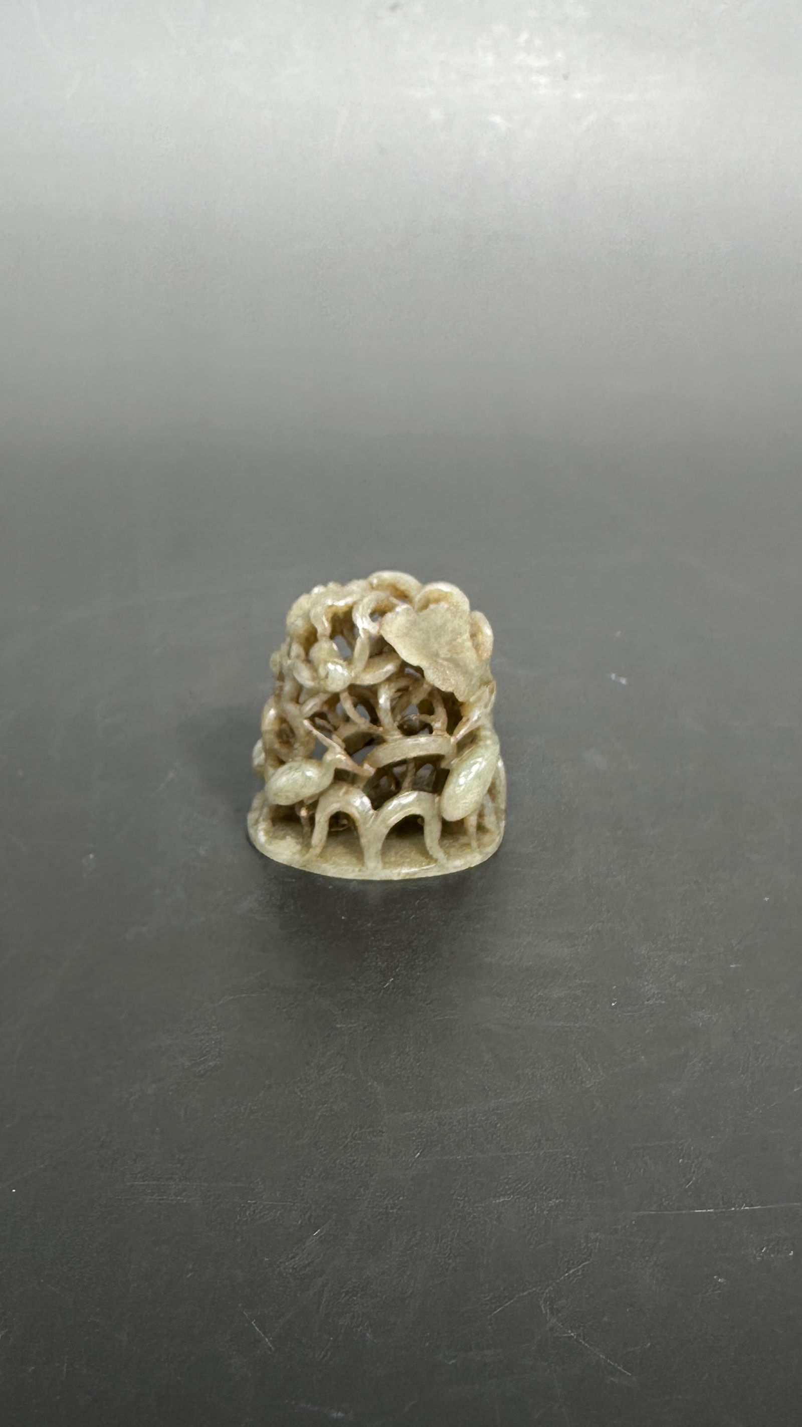 A Chinese Carved Reticulated Celadon Jade 'Egrets and Lotus' Hat Finial, Yuan Dynasty: Carved and pierced in the round with graceful egrets amid lotus leaves and budding blossoms. 1.5/8 in. high, 1.5/8 in. wide. A close comparable please see a finial in Shanghai Museum, https://www.shan