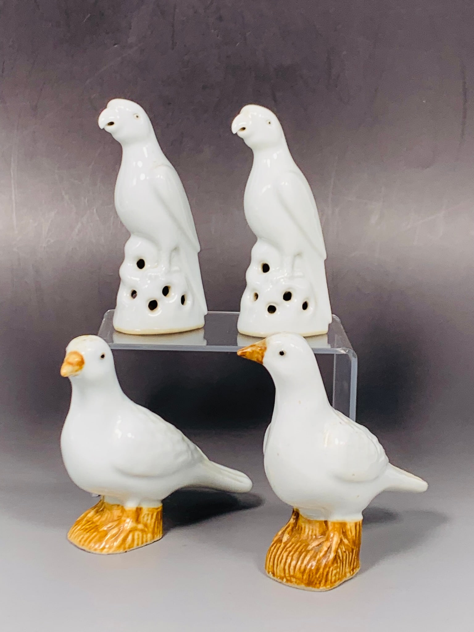 Two Sets of Chinese White-Glazed Figures of Birds: Comprising a pair of figures of doves, with the taller one measures 4.1/8 in. high, 4 in. wide; and a pair of figures of parrots, 4.3/8 in. high, 2 in. wide each.