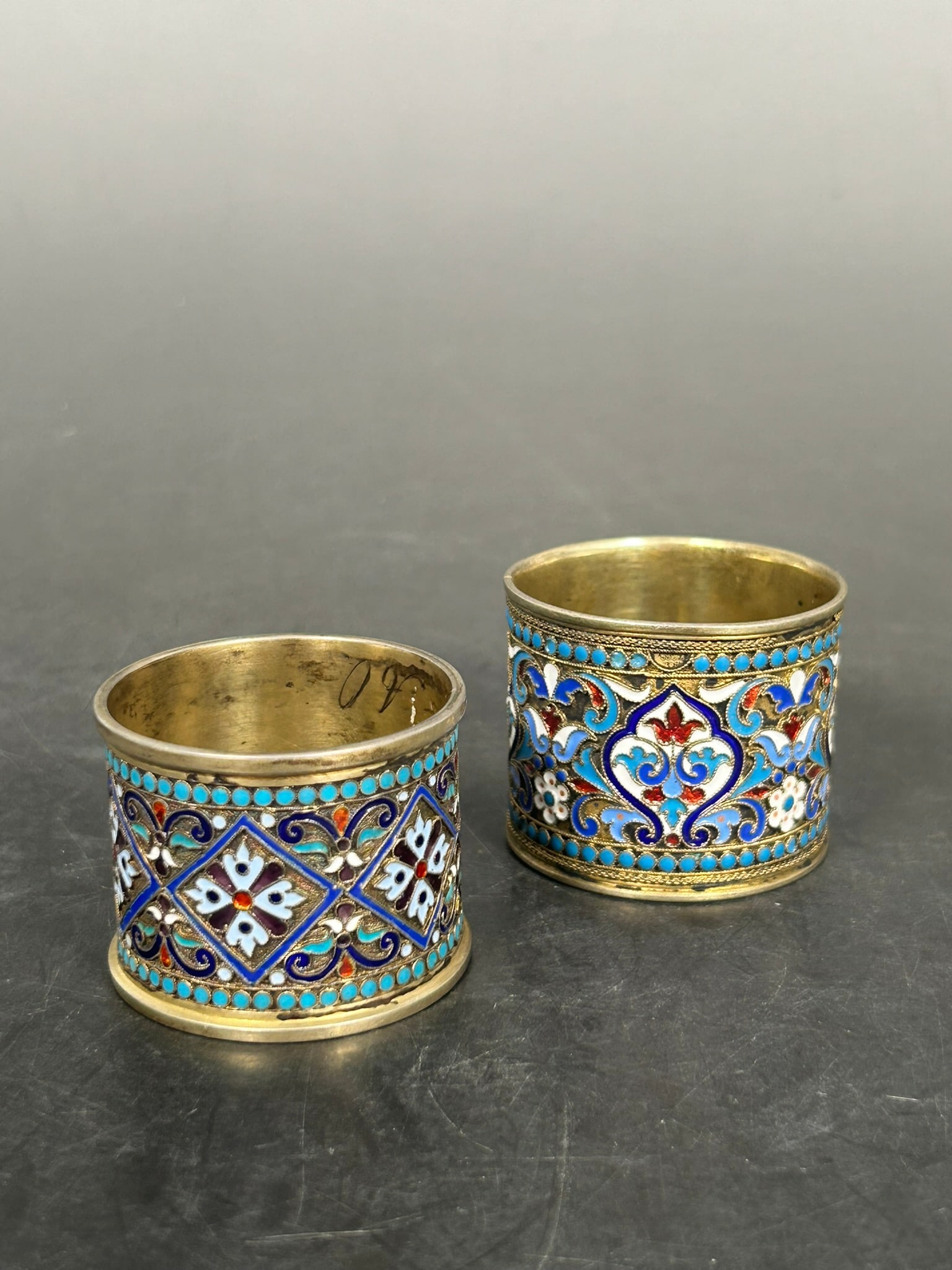 Two Antique Russian Silver and Cloisonne Enamel Napkin Rings: Hallmarks to the interior of both rings; the larger one measures 1.3/4 in. diam., 1.1/2 in. wide; the smaller one measures 1.3/4 in. diam., 1.3/8 in. wide.