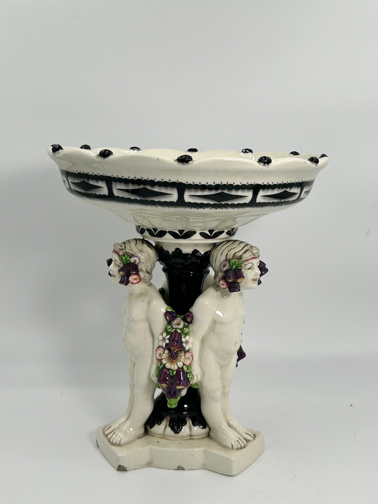 A Large Centerpiece with Three Putti, Hohenstein Mark: Marked underneath with workshop mark, Hohenstein manufactory stamp, model number 1004, and number 5. 12.3/4 in. high, 11.1/2 in. wide.