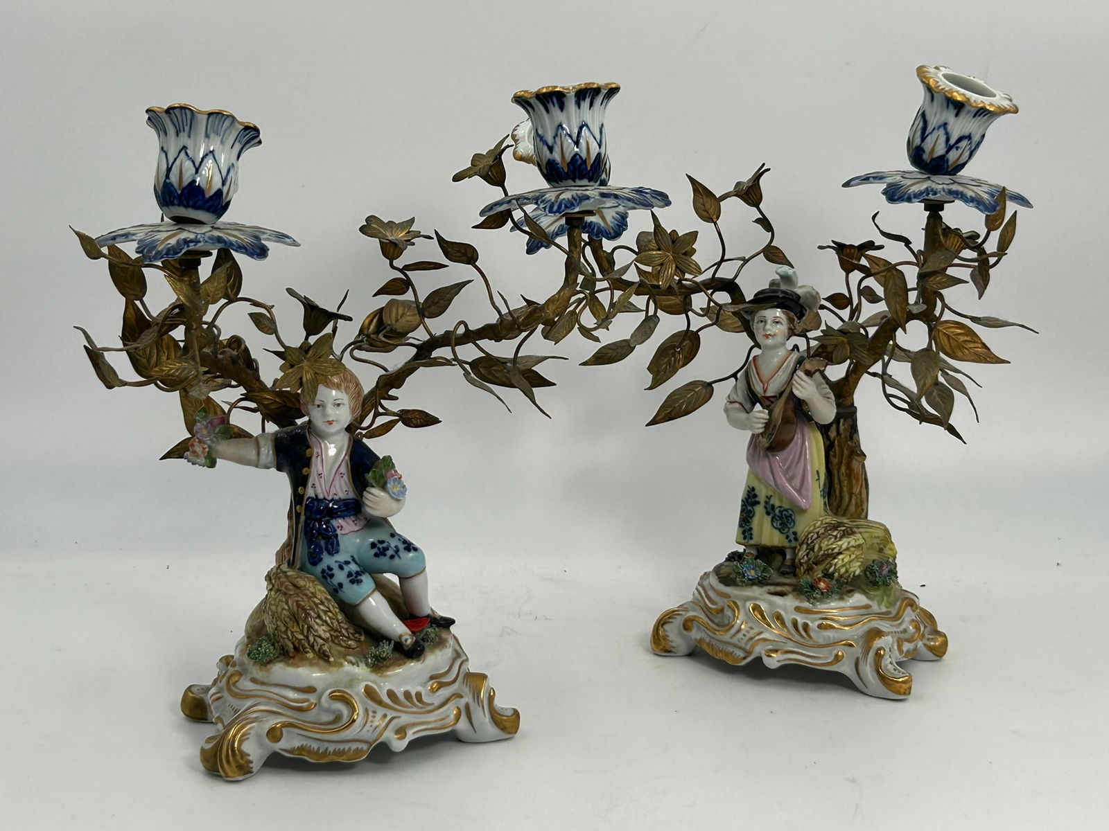 A Pair of Antique Italian Capodimonte Candelabra: Both with Capodimonte marks to the undersides. 10.1/4 in. high, 8.1/4 in. wide each.