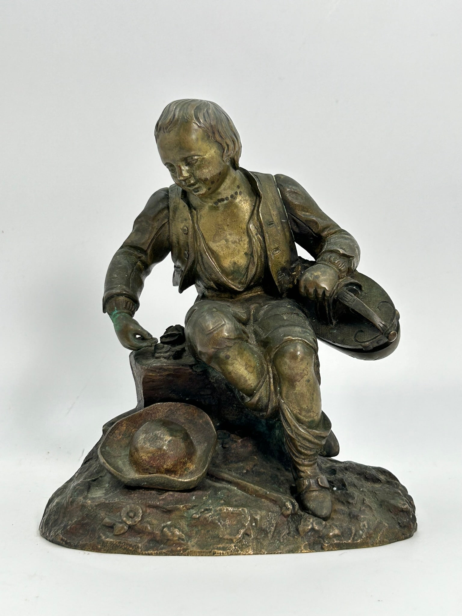 A Bronze Figure of a Seated Boy: 7.1/4 in. high, 6.1/2 in. wide.