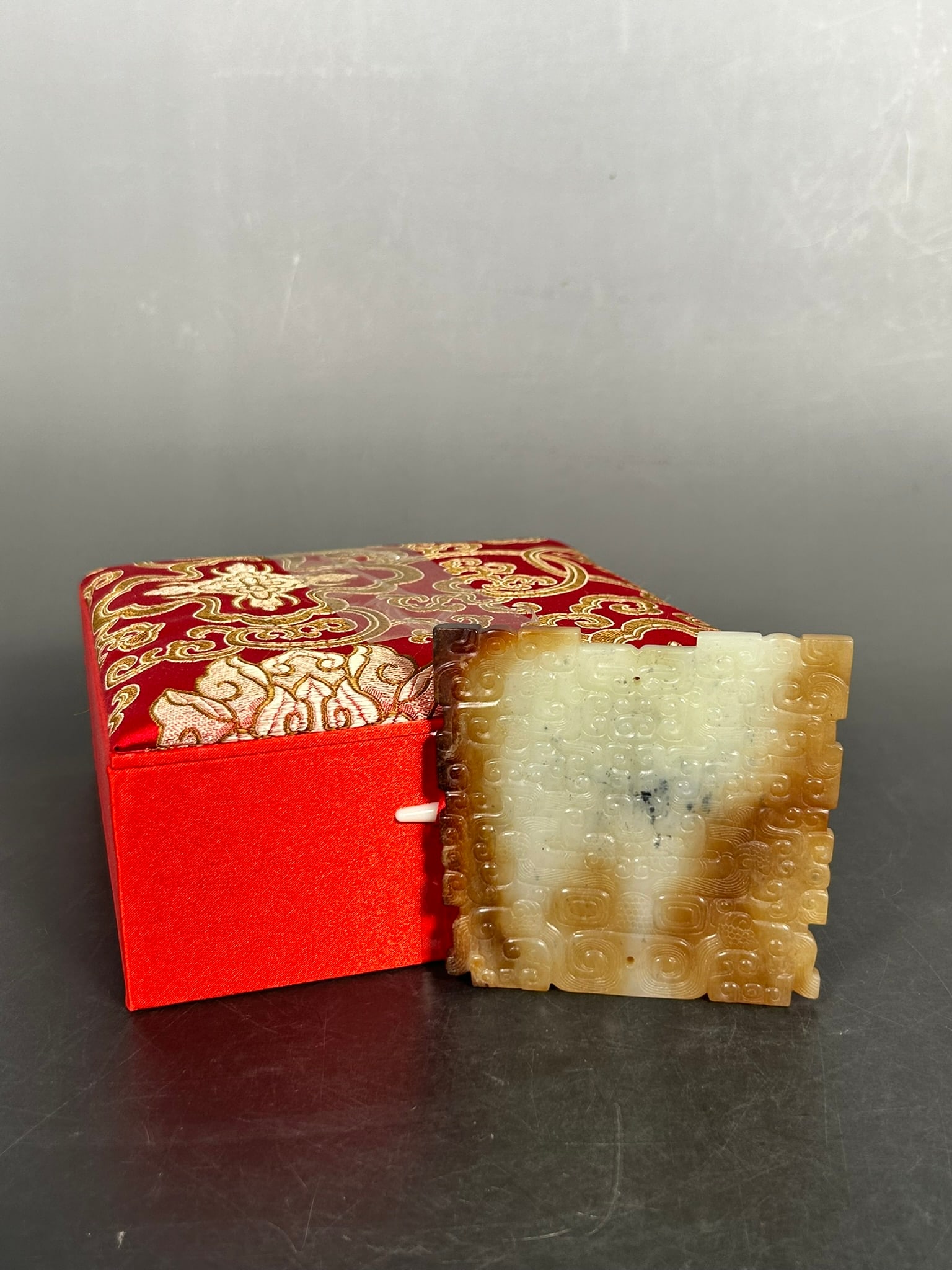 A Chinese White and Russet Jade 'Mask' Plaque, Han Dynasty: 3.1/2 in. long, 3.1/4 in. wide. Cloth box.