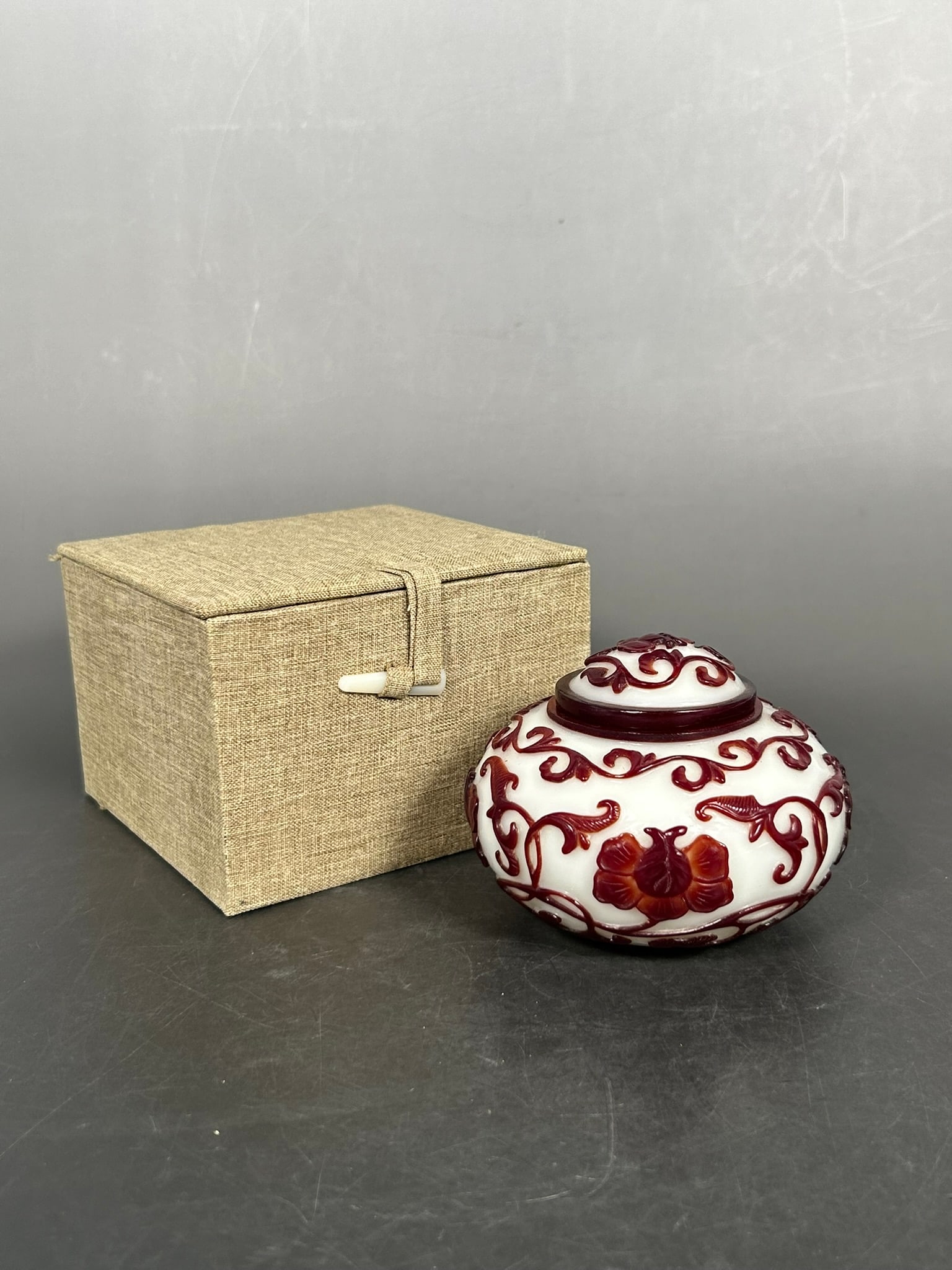 A Chinese Red-Overlay Glass Jarlet and Cover: Apocryphal Qianlong mark to the underside. 3 in. high, 3.3/4 in. wide. Cloth box.