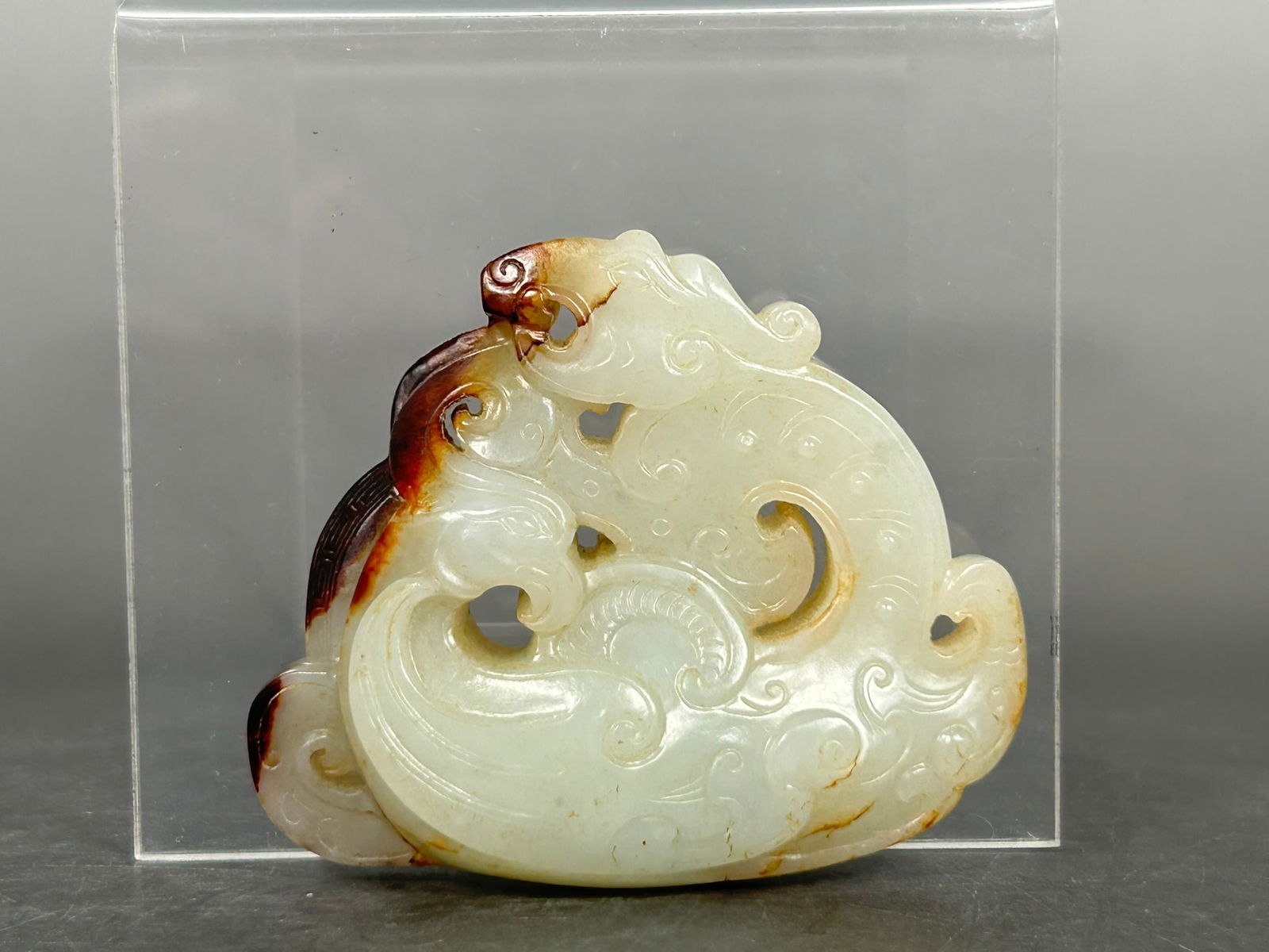 A Chinese Carved White and Russet Jade 'Dragon and Phoenix' Pendant: 2.1/4 in. long, 2.1/4 in. wide.